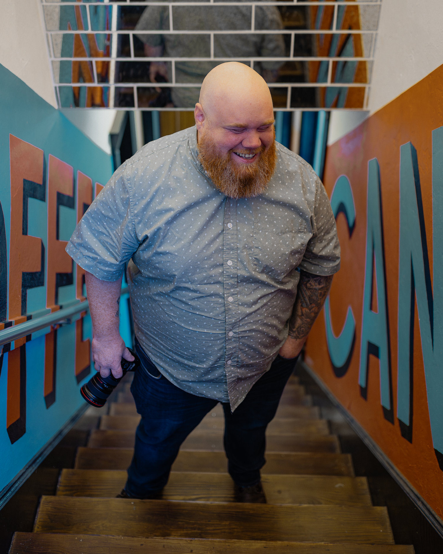 Savannah portrait photographer David Monroe — A man with a long beard and bald head is walking up a staircase in a colorful hallway.