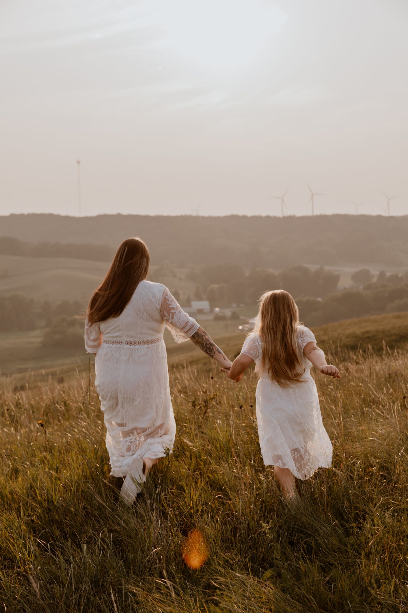Mother and daughter walking through golden field during sunset lifestyle portrait session in Lake Benton Minnesota