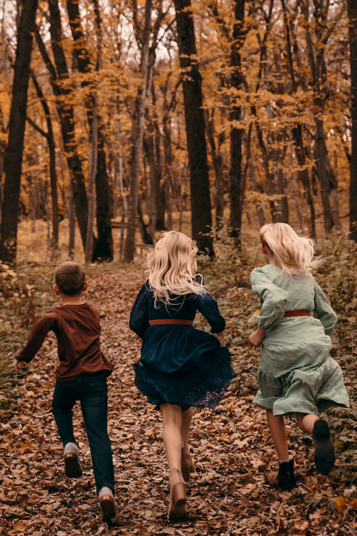 Children running through fall leaves during outdoor lifestyle photography session in Lynd, Minnesota at Camden State Park