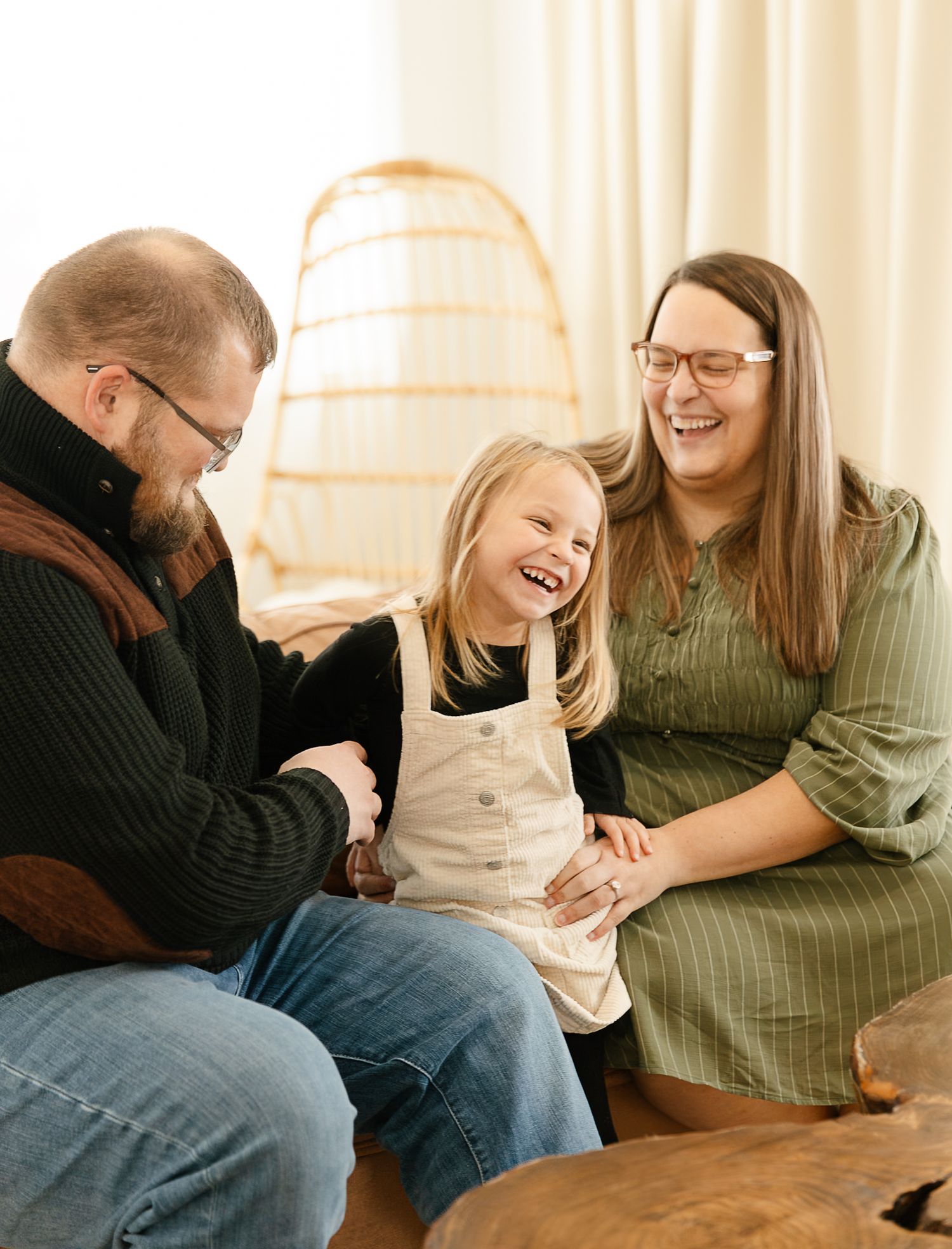 Family sharing joyful moments and laughter while sitting together on a brown leather couch in a warmly lit studio in Elkton SD