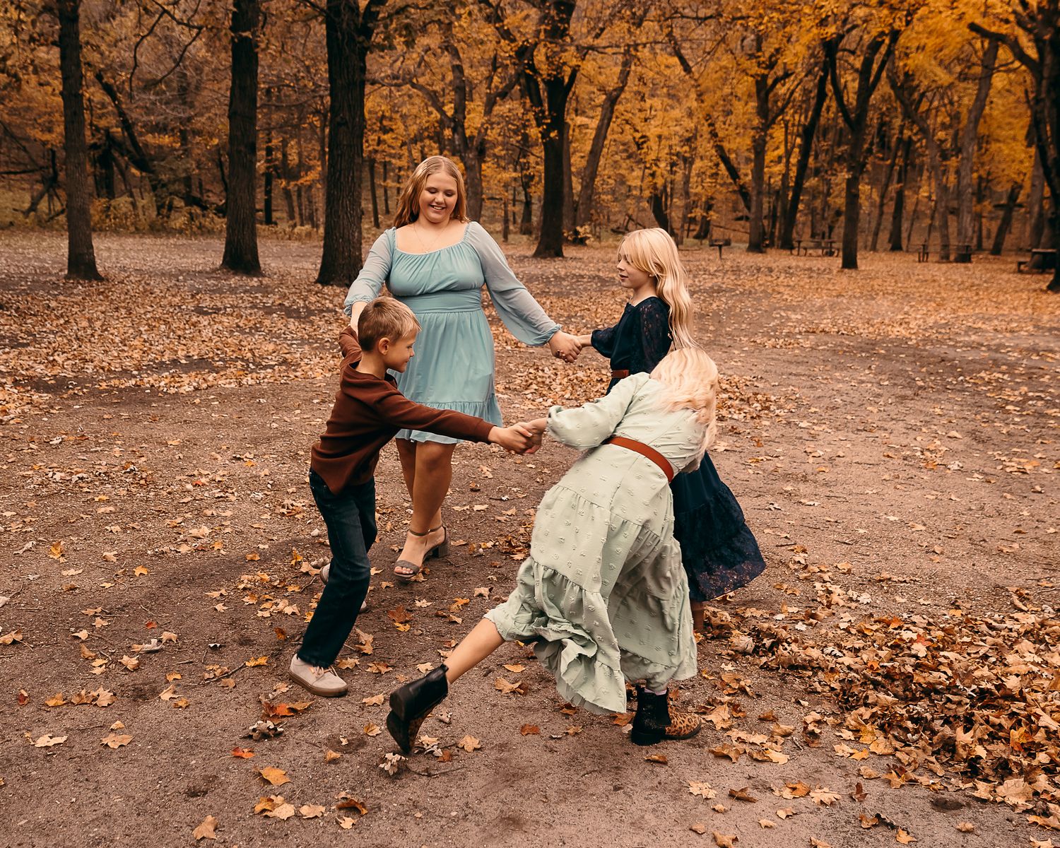 young brother and sisters playing ring around the rosey in fall foilage in Lynd MN at camden state park