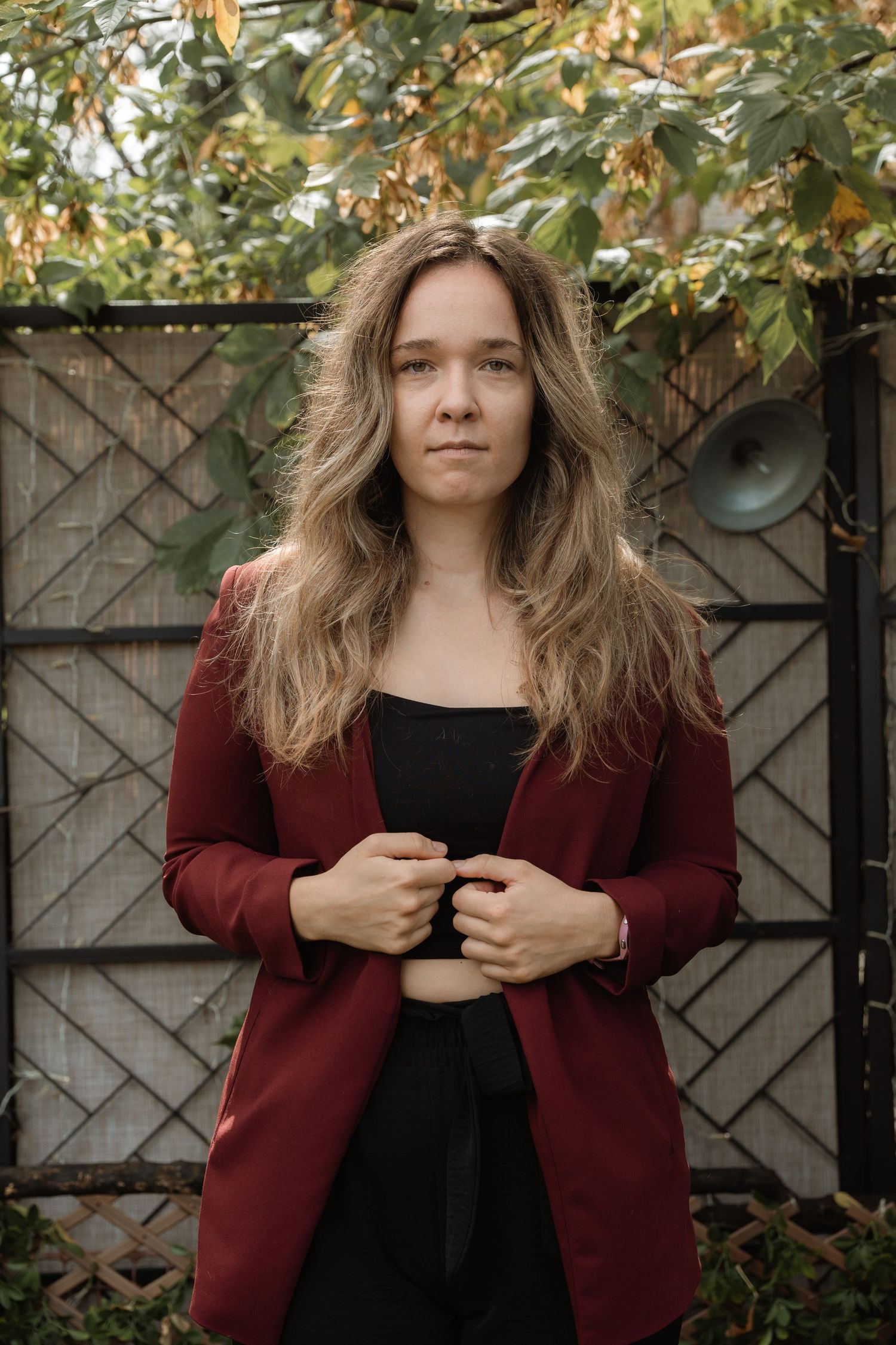 Four outdoor portrait photos showing someone wearing a burgundy cardigan and black top against a wooden fence backdrop.
