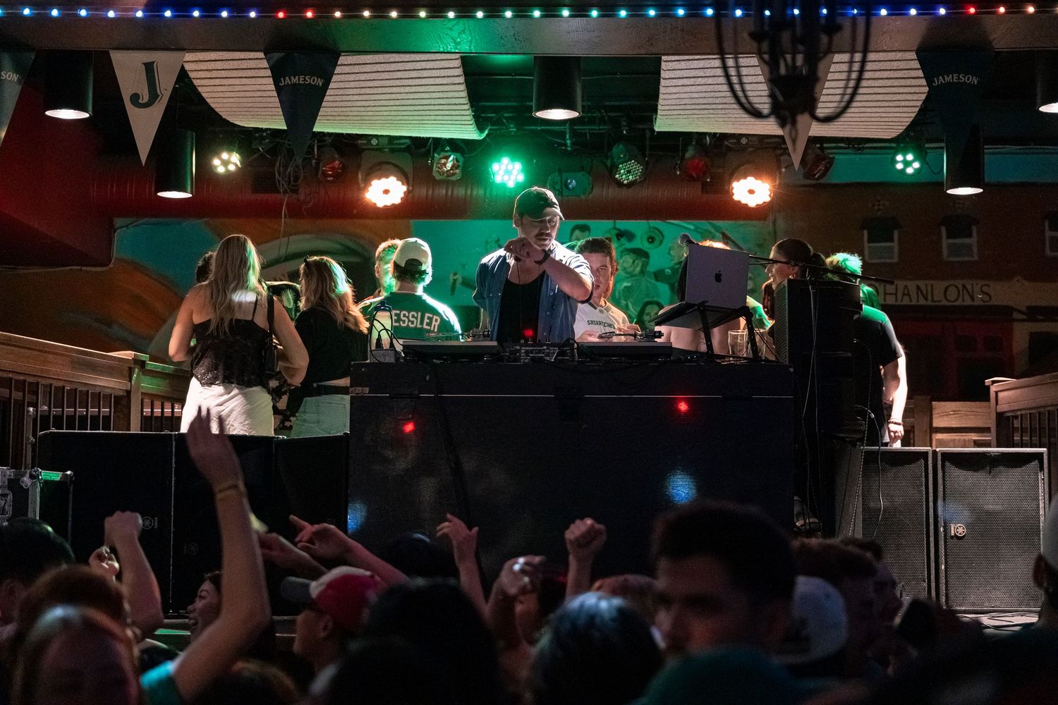 People dancing together in a dimly lit nightclub with green and blue lighting illuminating the space.