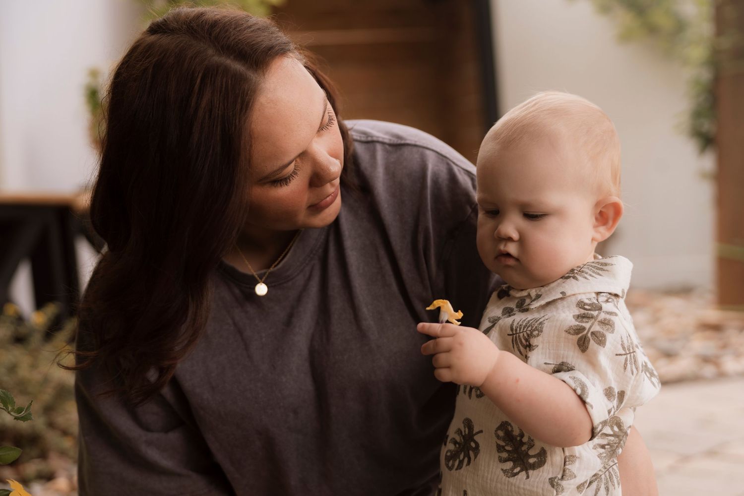 Tender feeding interaction between caregiver and infant in outdoor setting.Regina Saskatchewan Family portrait photographer.