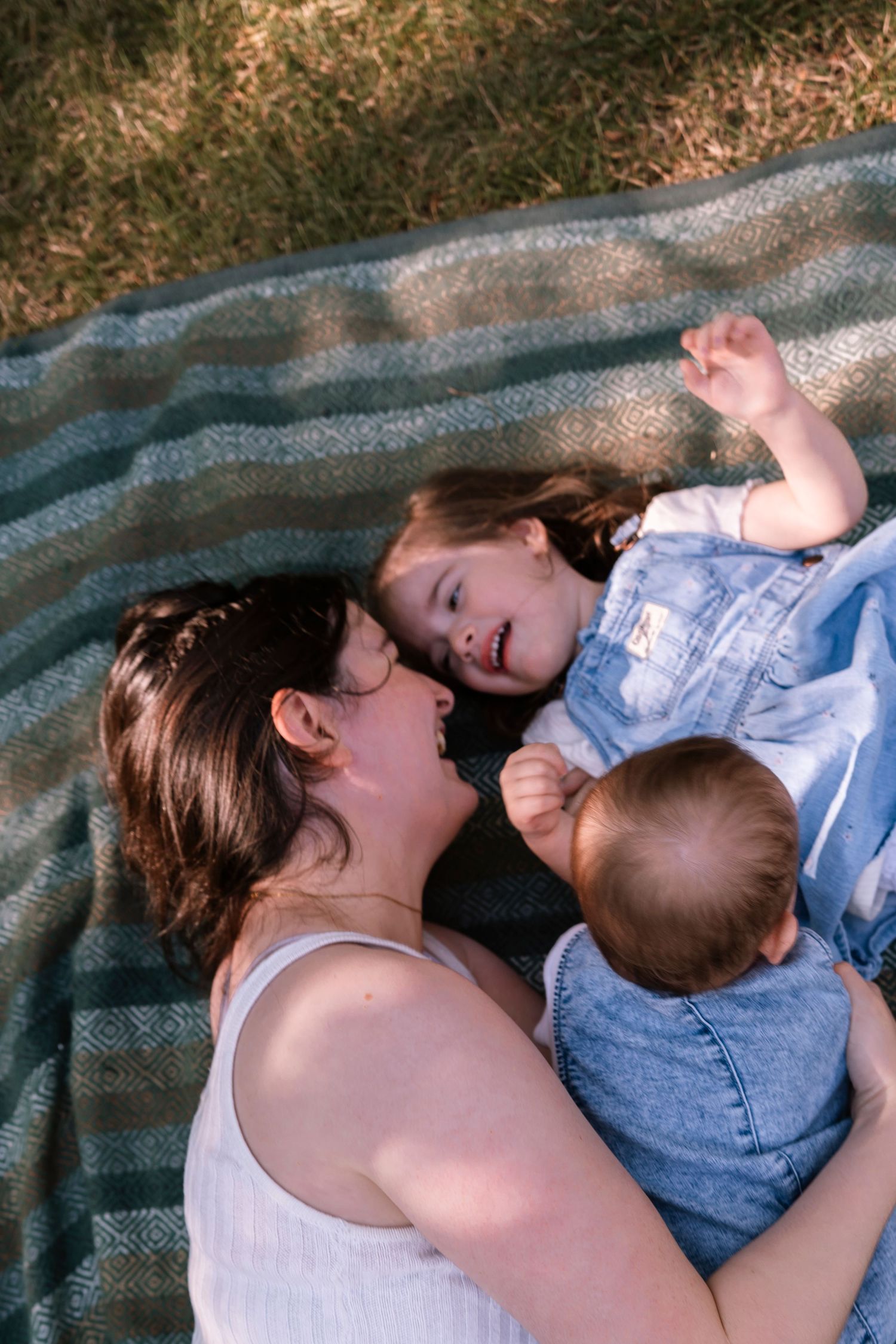 Photos showing a tender moment between parent and baby resting together on a blue blanket. Regina Saskatchewan Family portrait photographer.