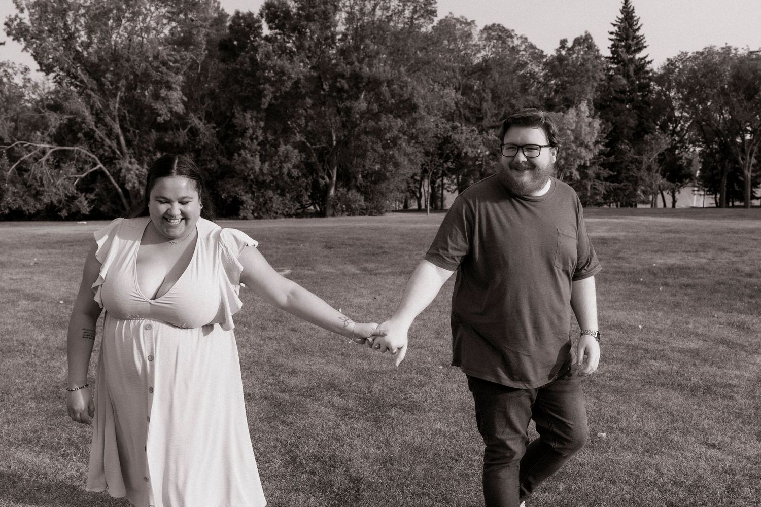 A couple poses together in an outdoor engagement photo session across multiple black and white frames in a grassy field.