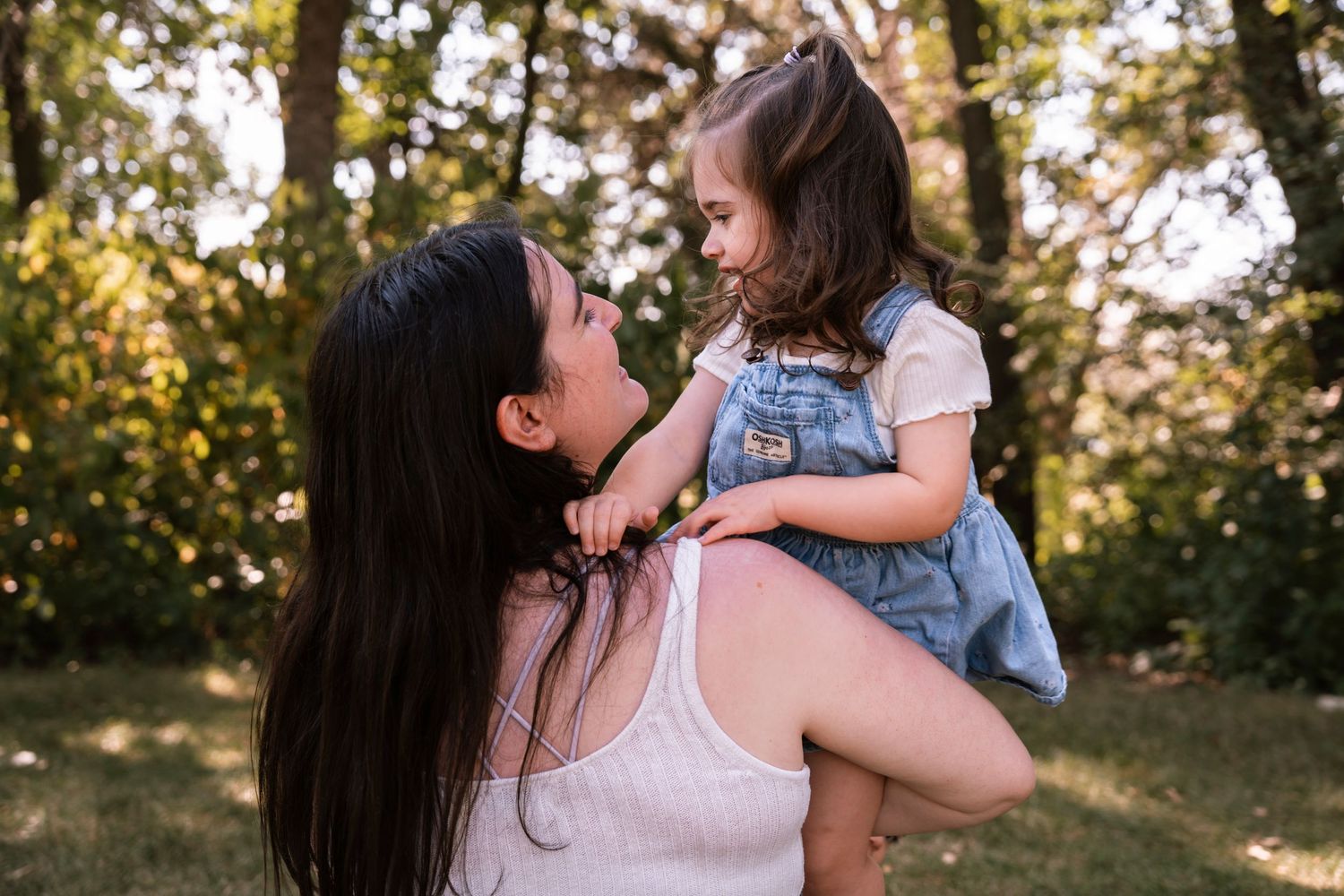 A joyful moment shared between two people embracing in a sunny outdoor setting with trees in the background.