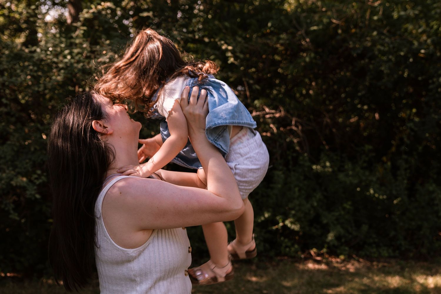 Family moment captured in outdoor natural setting with sunlight filtering through trees. Regina Saskatchewan Photographer.