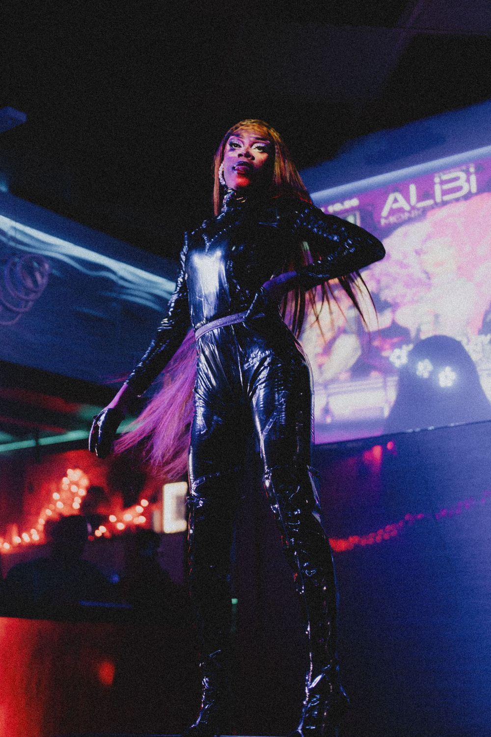 Performance scene in a nightclub with blue lighting and neon signage.