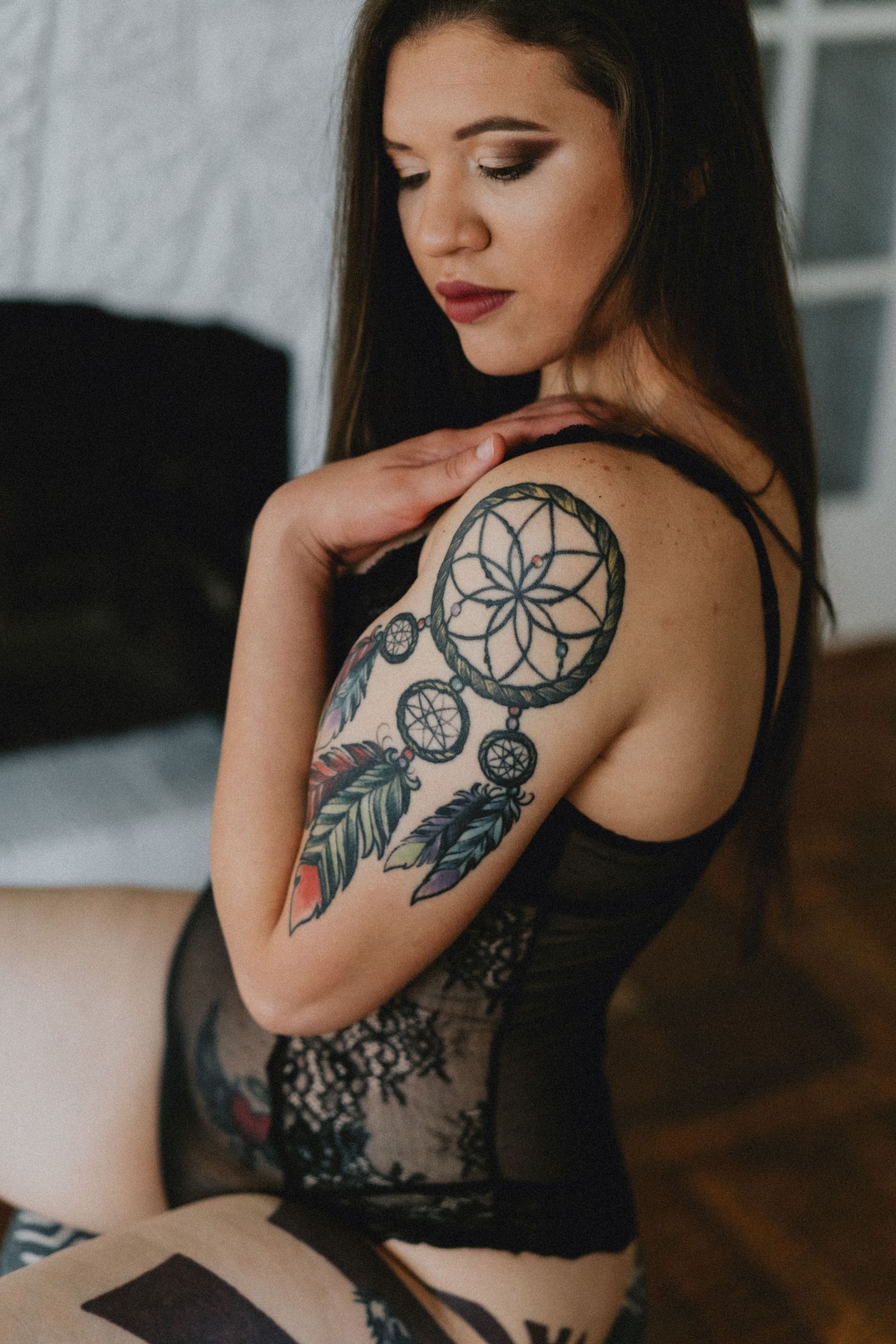 Close up of detailed dreamcatcher tattoo on shoulder with lace lingerie.