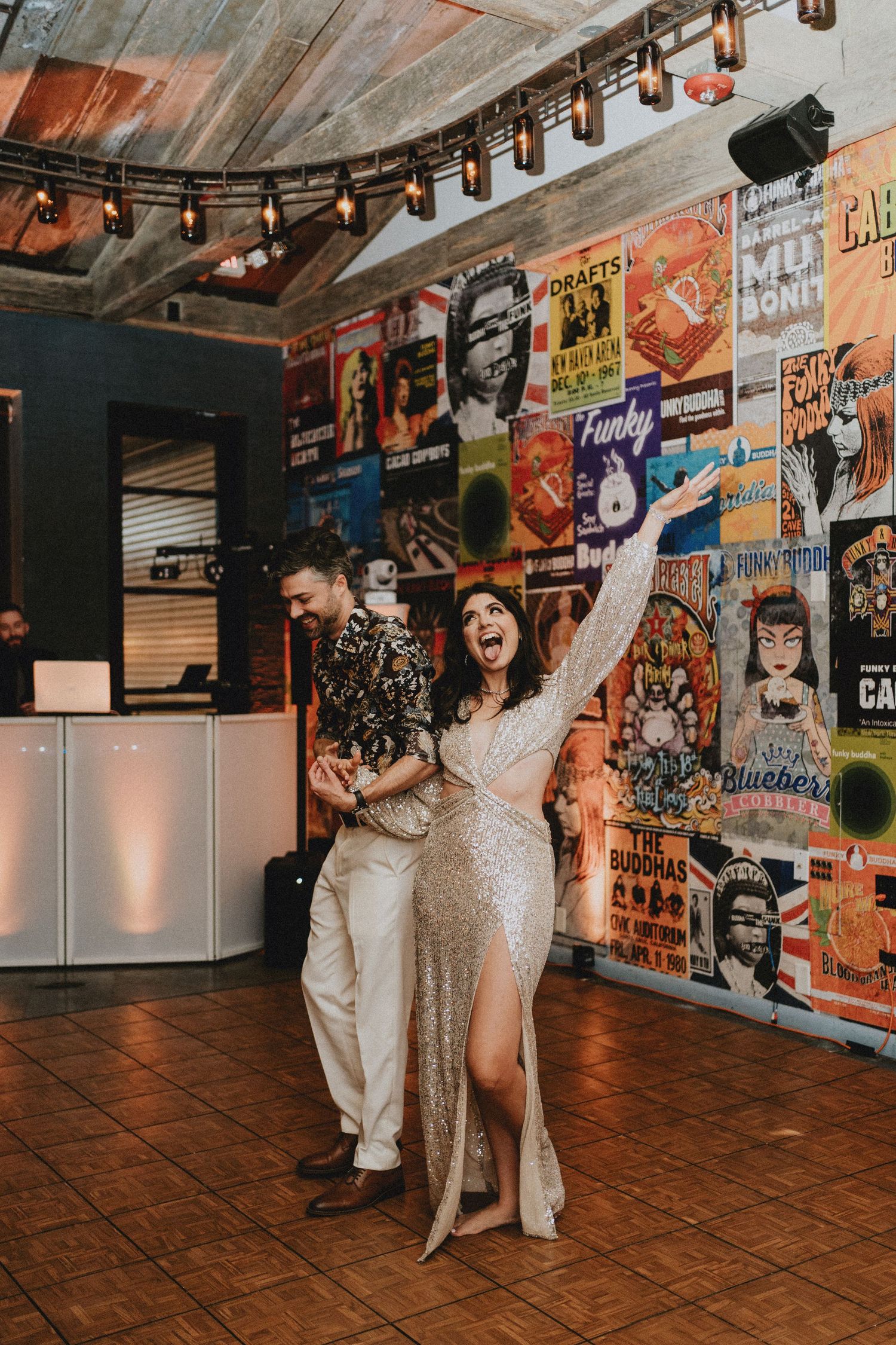 Bride in sequin gown celebrates joyfully with groom during grand entrance at eclectic concert venue wedding.