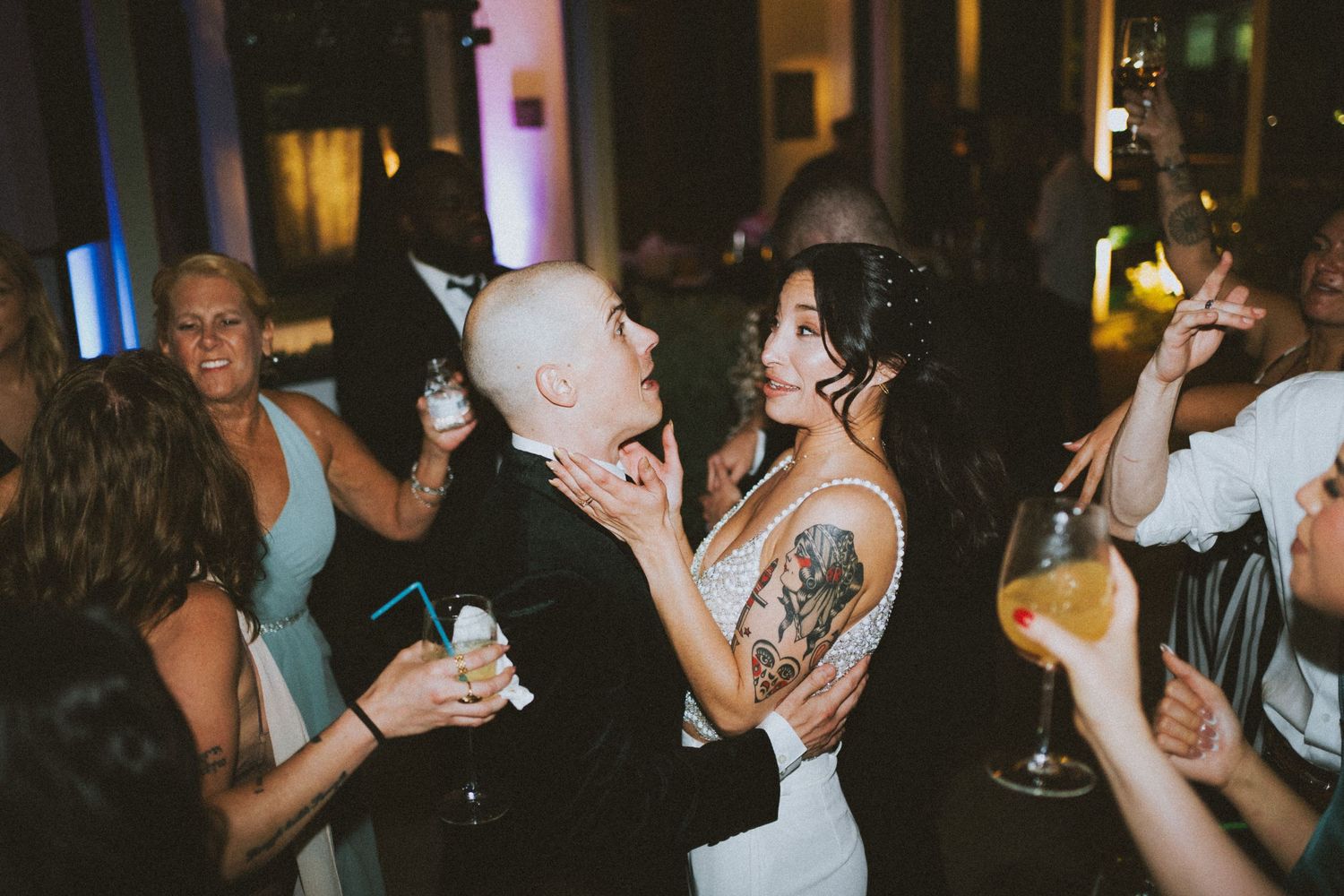 People dancing and socializing with drinks at a dimly lit nightclub or party venue.