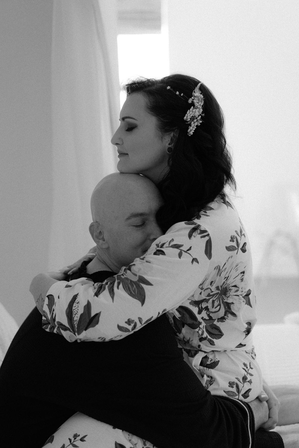 Intimate black and white portrait of couple embracing in floral dress.