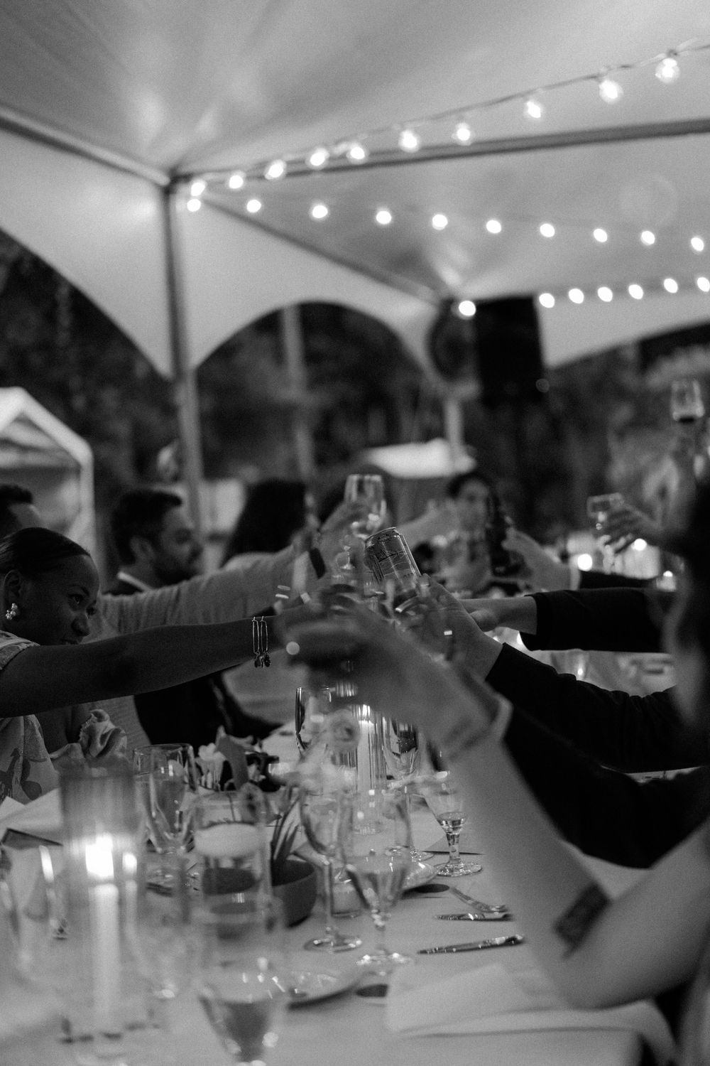 Wedding reception dinner table with string lights and glassware at dusk.