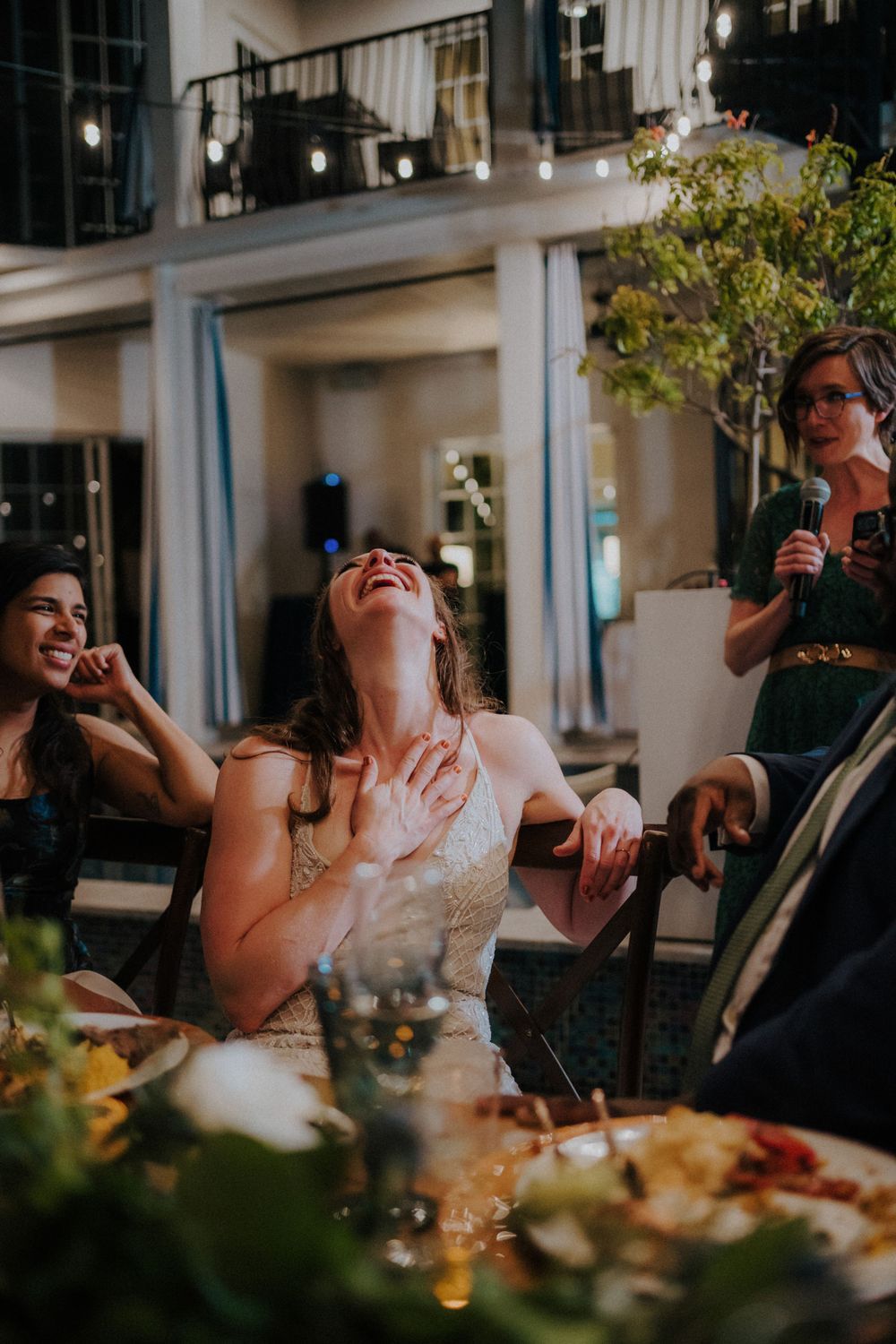Reception dinner guests enjoying laughter and conversation at elegantly set tables.