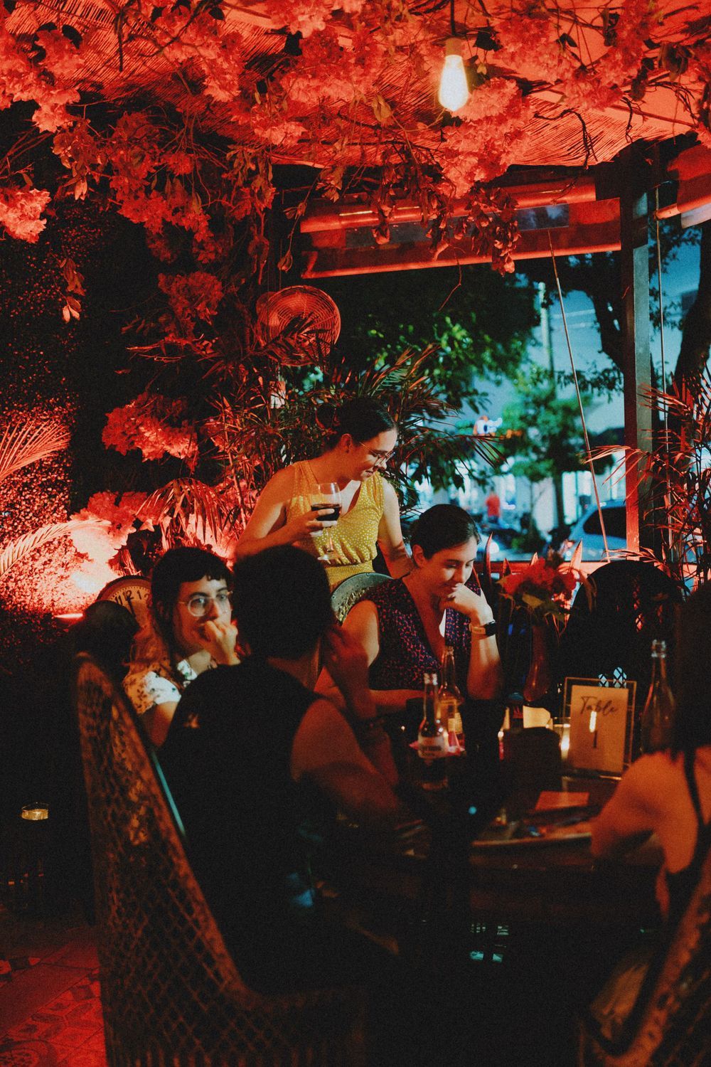 Vibrant red-lit party venue with people mingling under dramatic lighting.