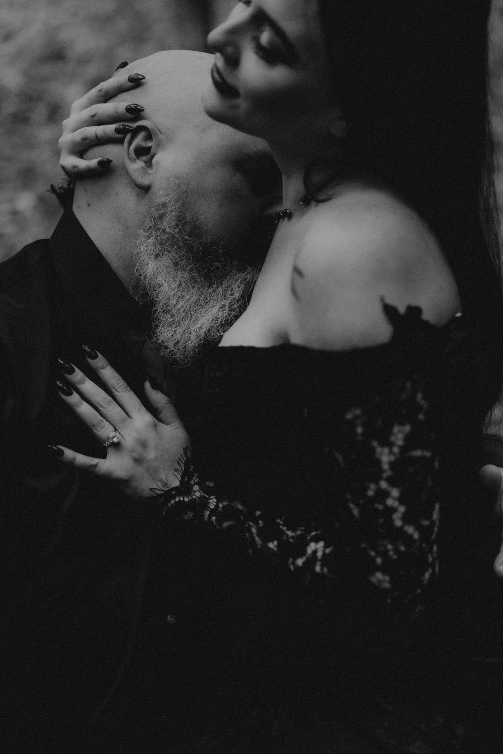 Intimate black and white portrait of couple sharing tender moment in dark setting.