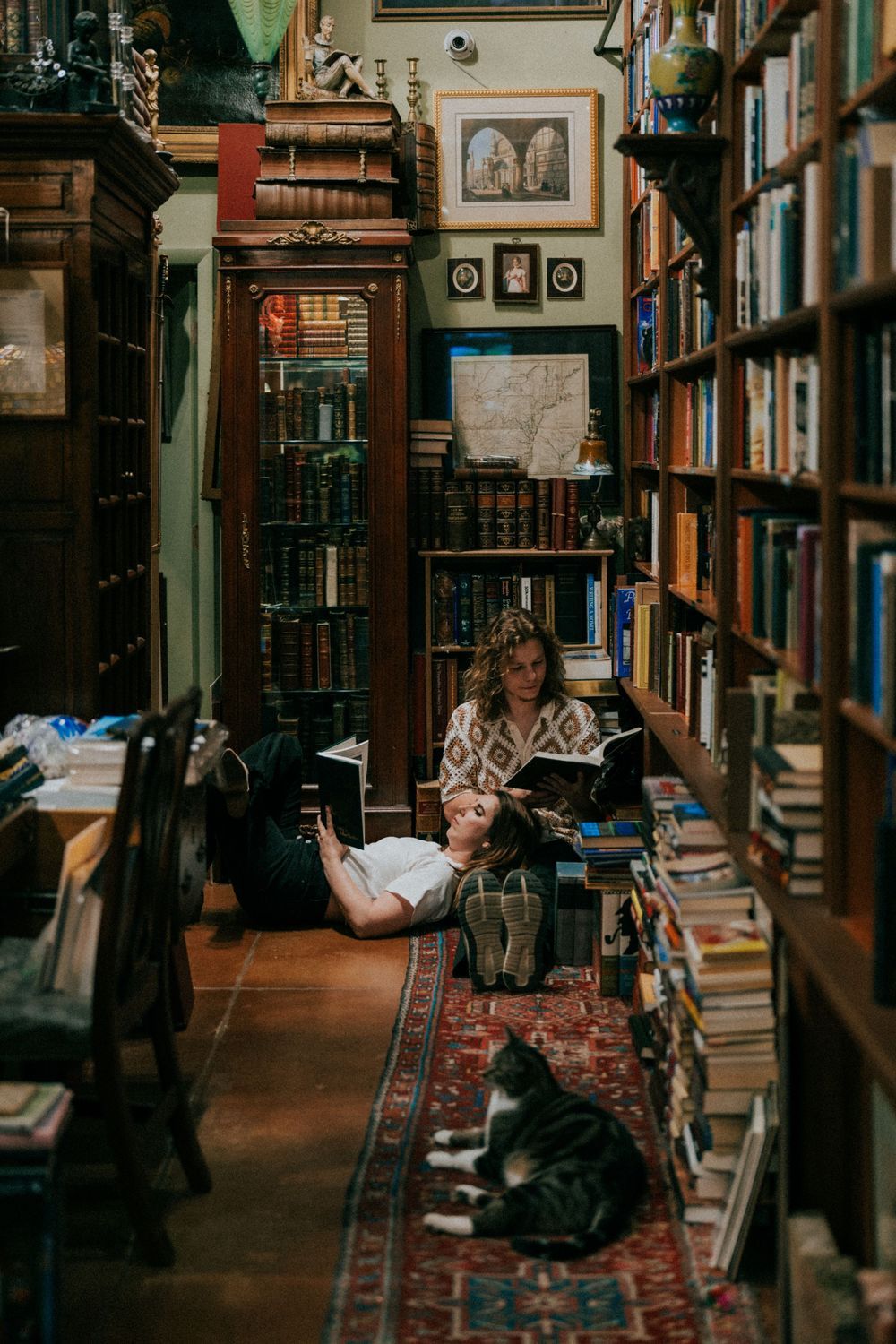 A couple explores a vintage bookstore with warm lighting and packed bookshelves.