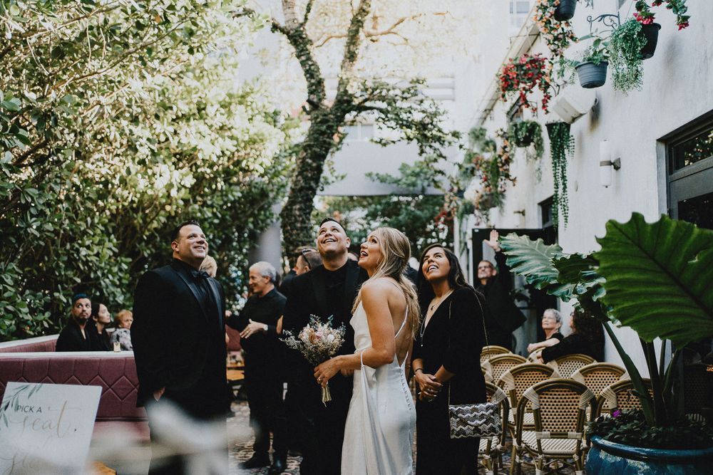 Wedding ceremony in a lush garden setting with guests seated under natural greenery.