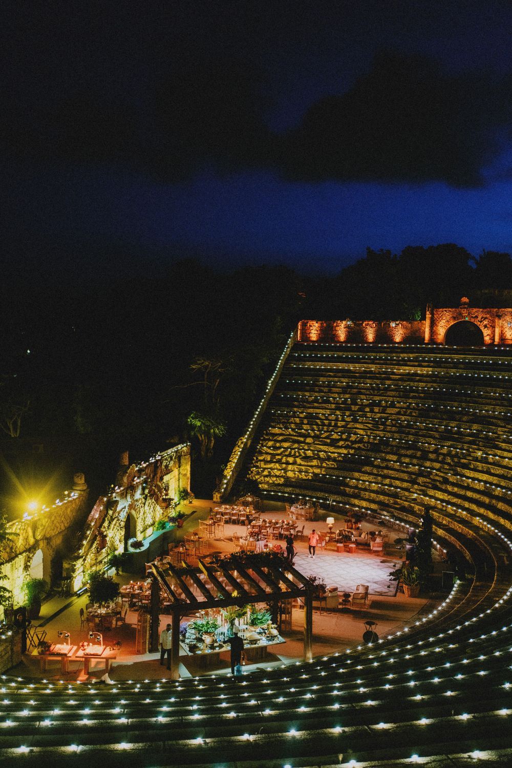 Illuminated amphitheater at night with rows of glowing lights creating a dramatic atmosphere.