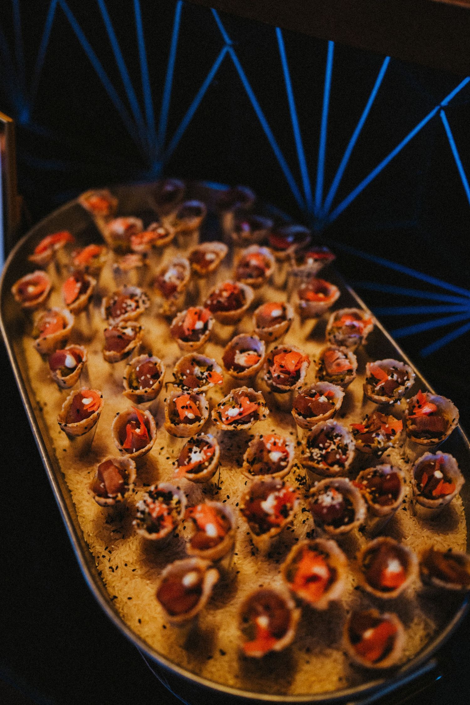 Elegant tray of mini taco cups filled with savory toppings, served as appetizers at an upscale event.