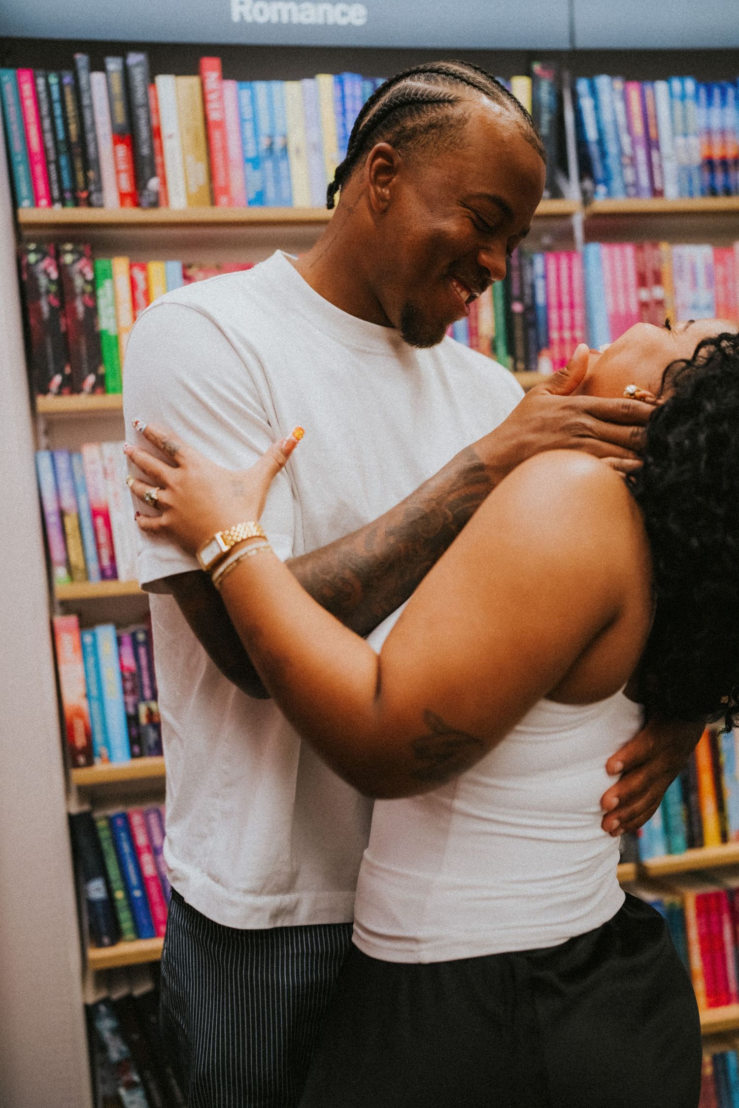 Smiling couple embracing tenderly in the romance section of a bookstore.