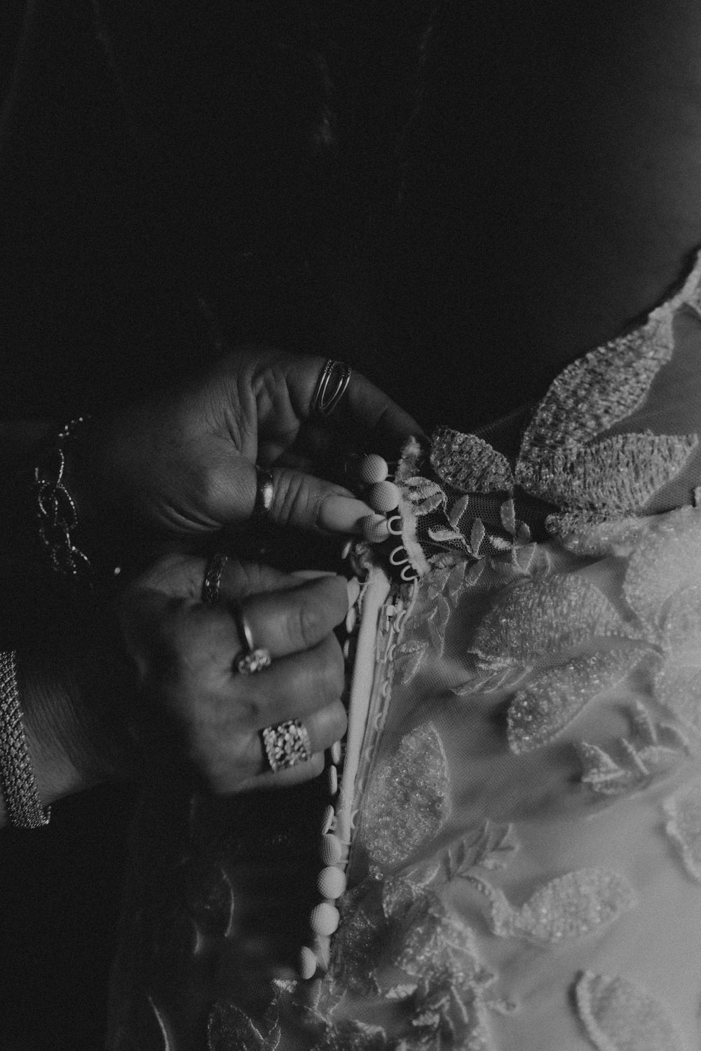 Close-up artistic black and white shot of intricate lace wedding dress details.