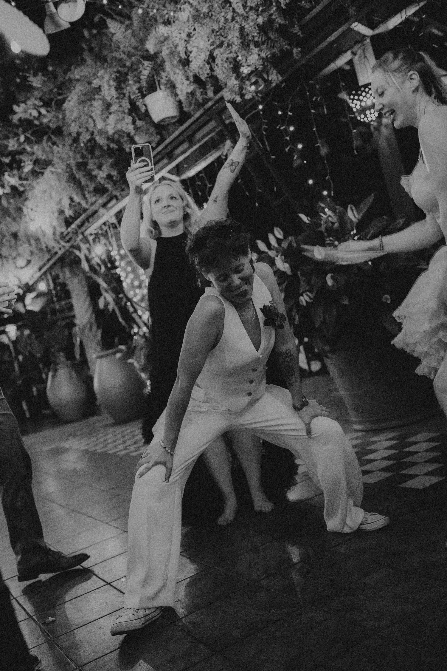 Bride dancing energetically on black and white checkered dance floor at wedding reception.