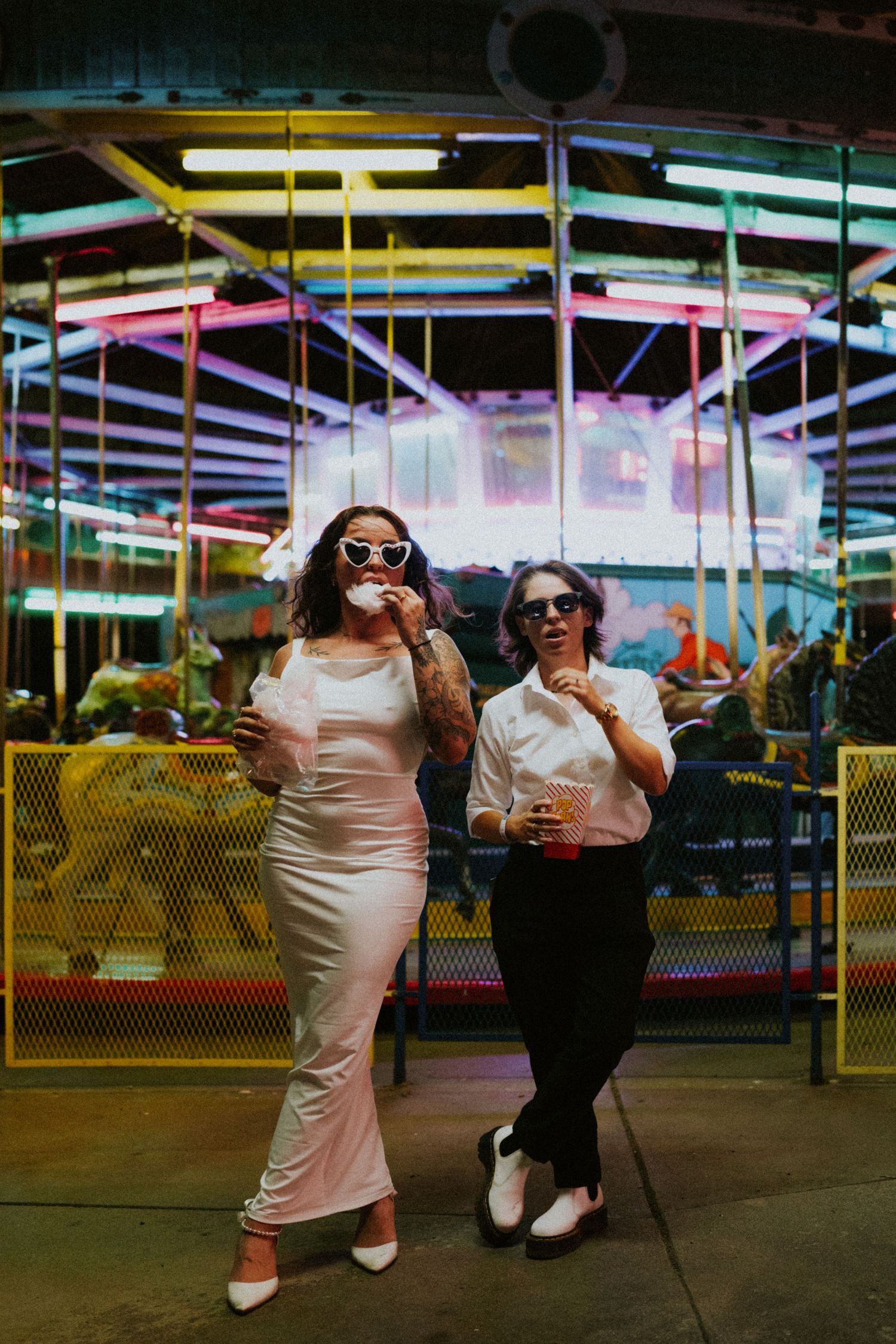 Retro-styled photo of people posing at a carnival with colorful neon lights in the background.