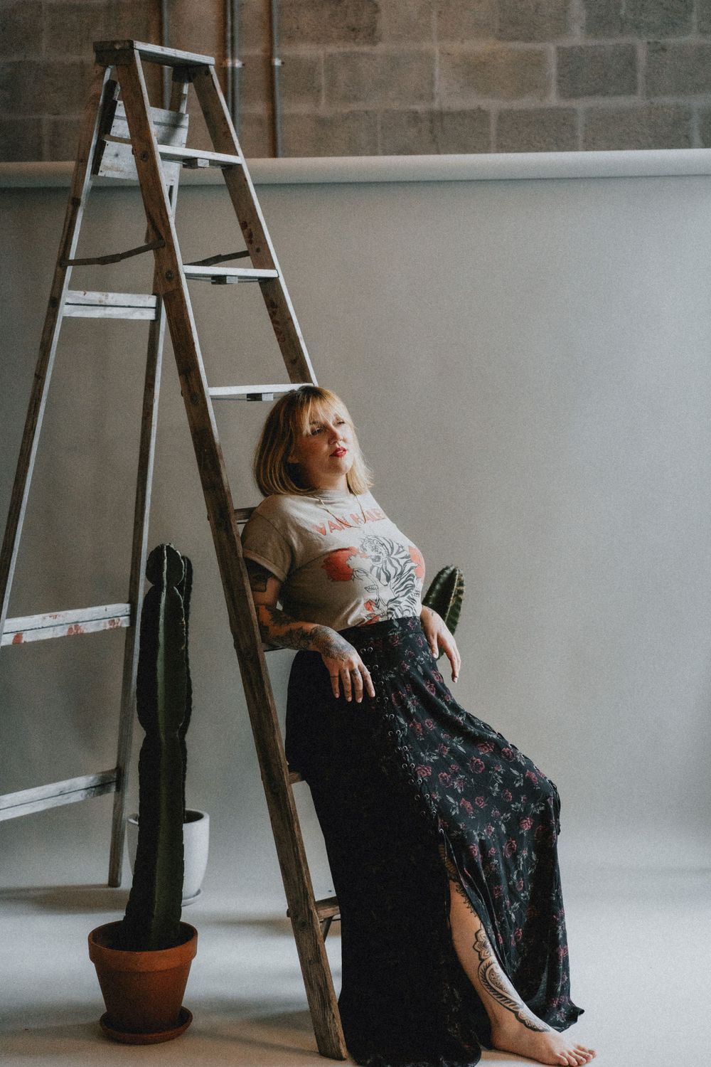 Artistic portrait series with person posing on wooden ladder in studio setting.