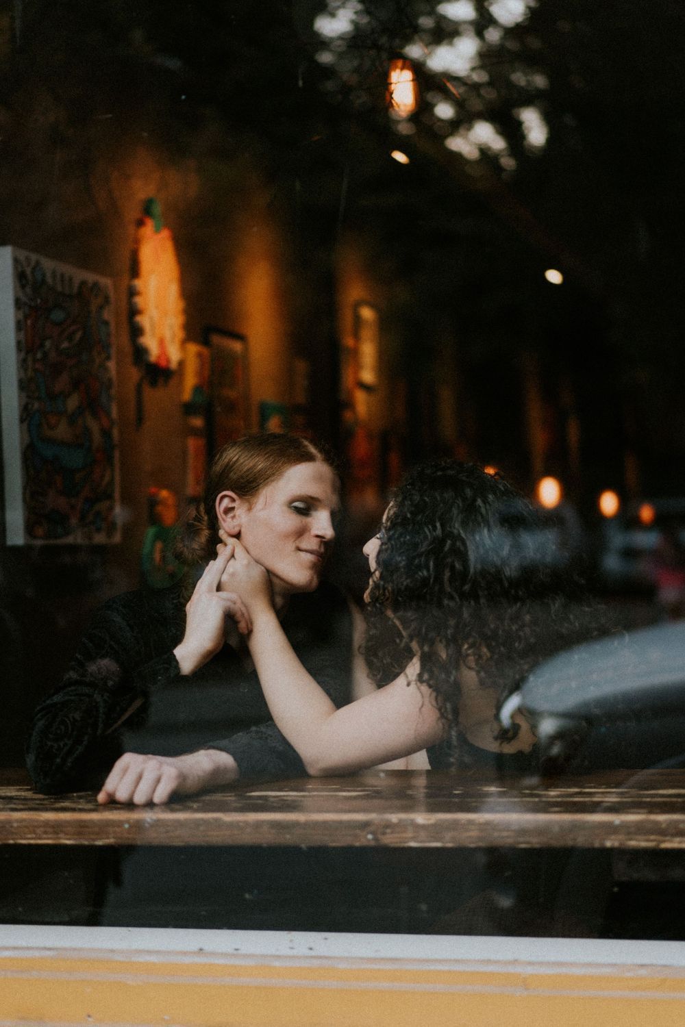Moody portrait in dark bar setting with warm ambient lighting.