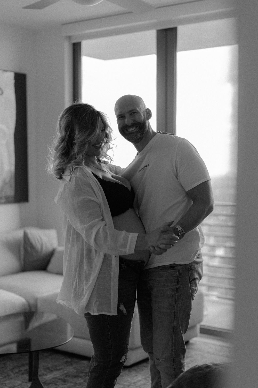 Black and white series showing a couple looking at ultrasound photos in a bright sunlit room.