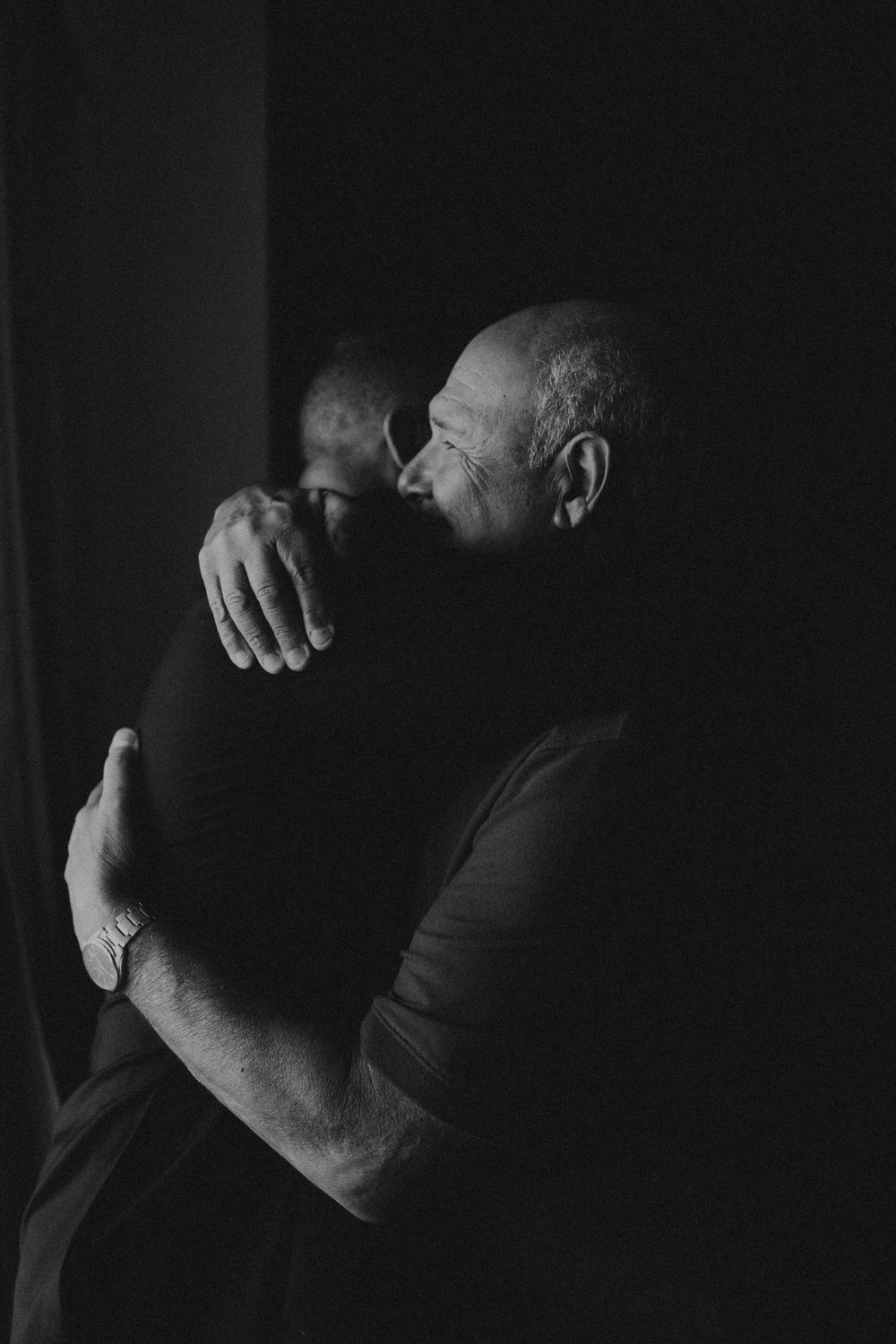 Intimate black and white portrait in dramatic lighting and shadows.