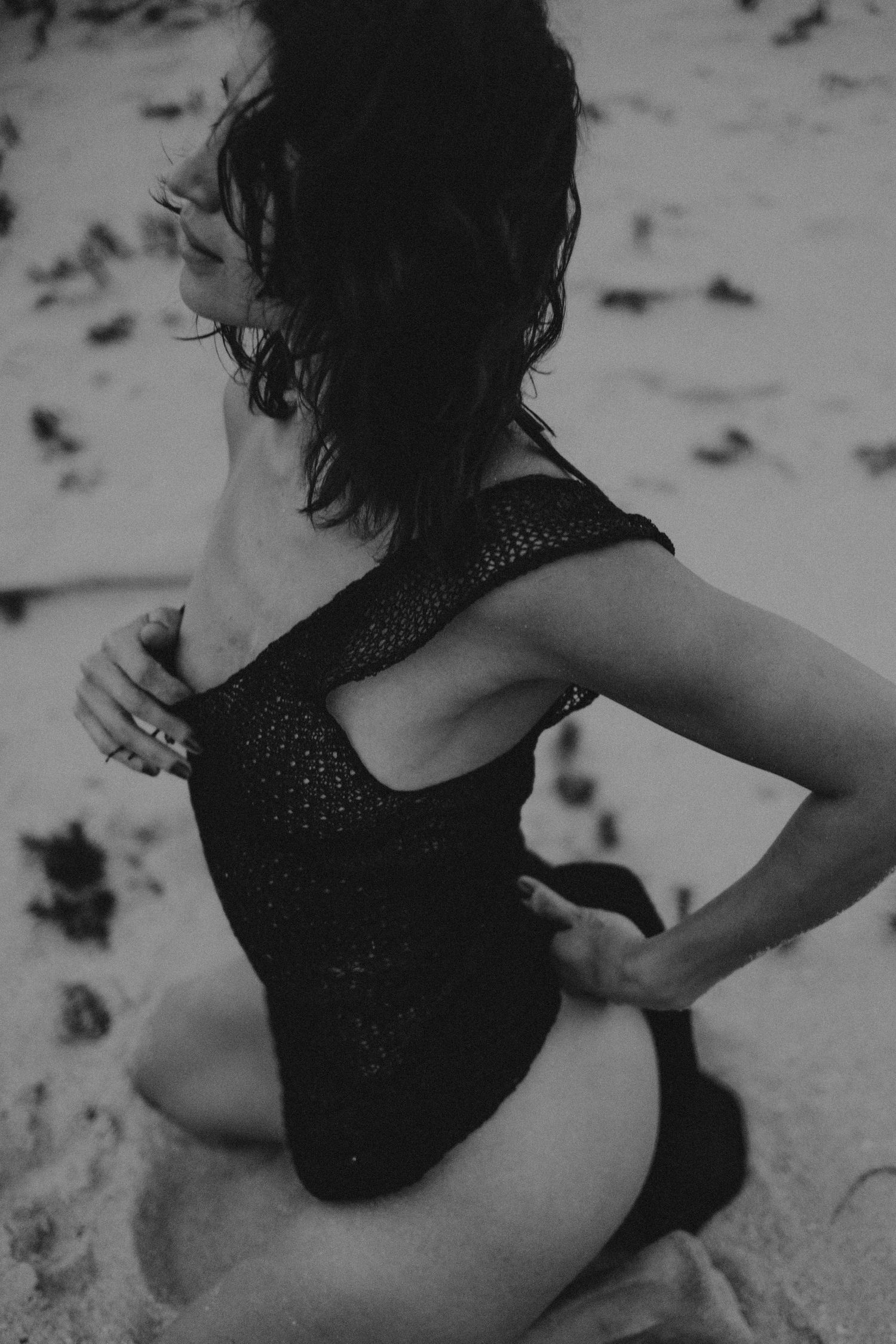 Silhouette of a figure twirling on a sandy beach in black attire.