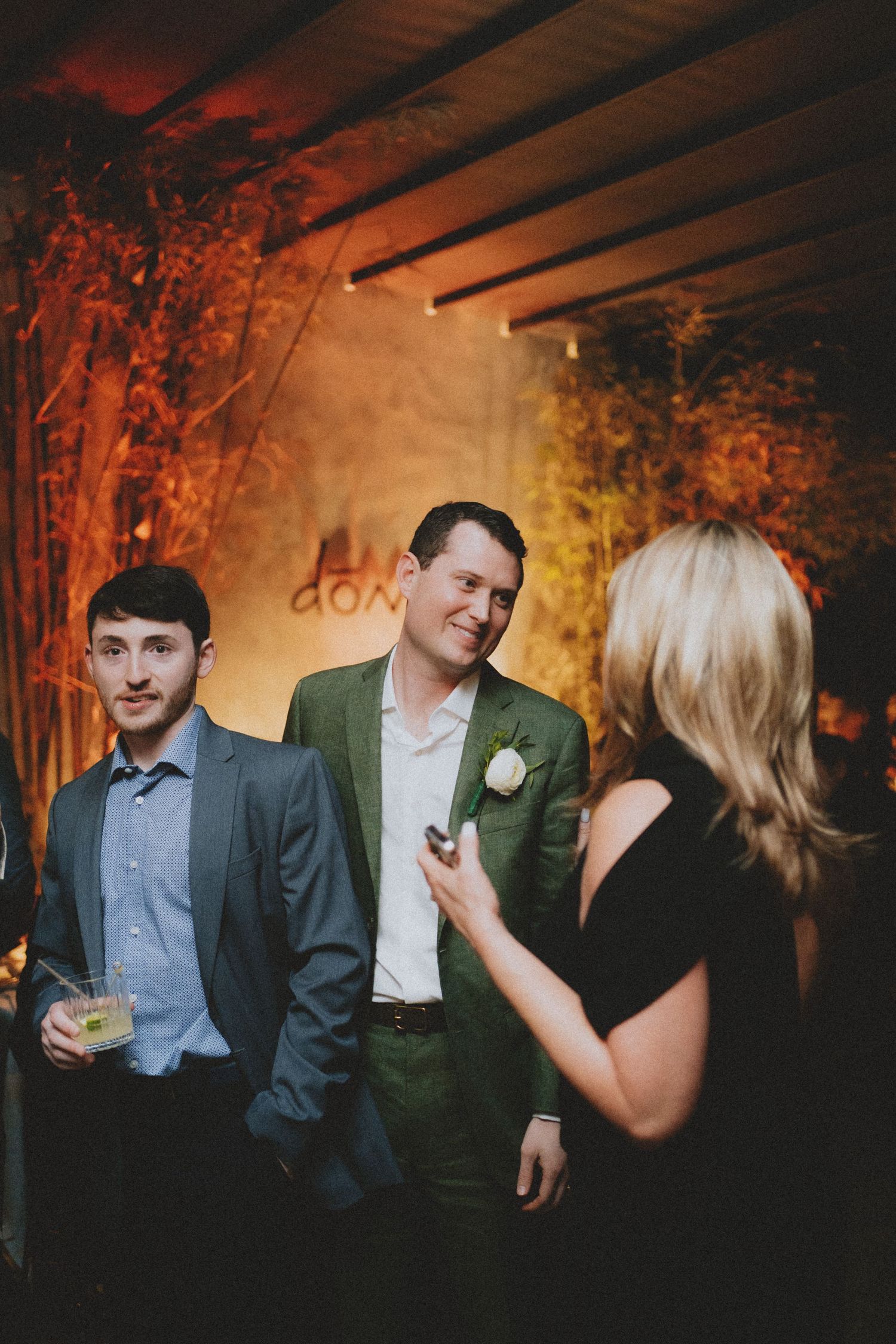 Wedding guests socializing at a warmly lit reception venue with autumn floral decorations.