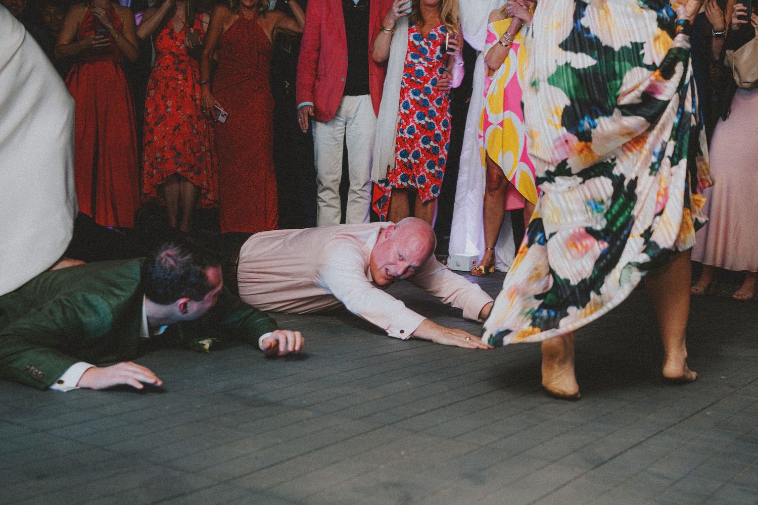 Guests doing the limbo on the dance floor at a lively wedding reception party.