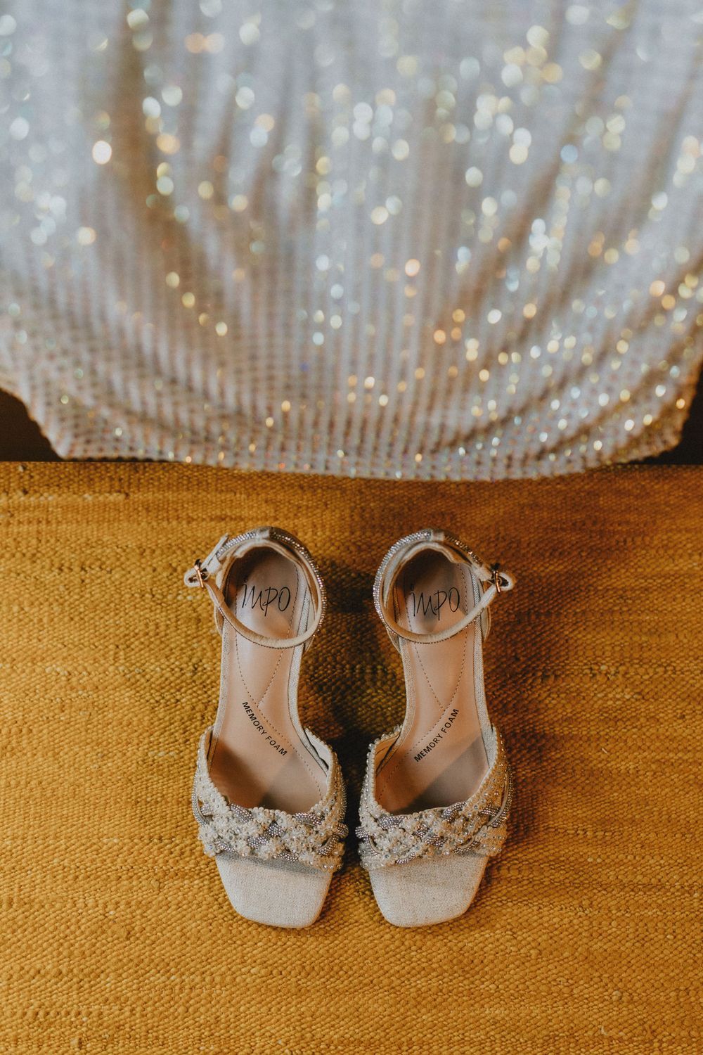 Elegant silver wedding shoes with sparkly details displayed on a wooden surface.