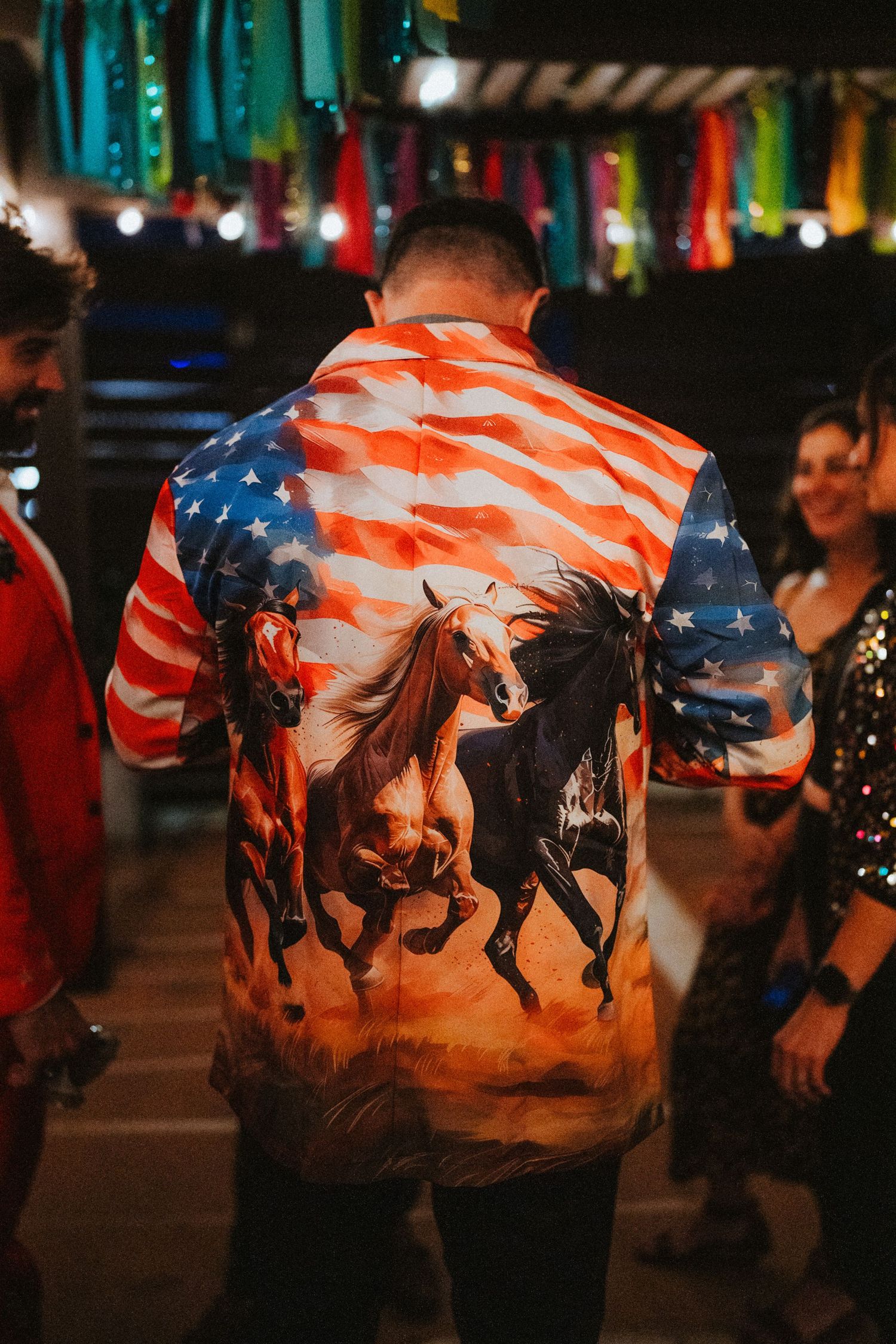 Man wearing an American flag shirt with wild horses at a festive party with colorful decorations.