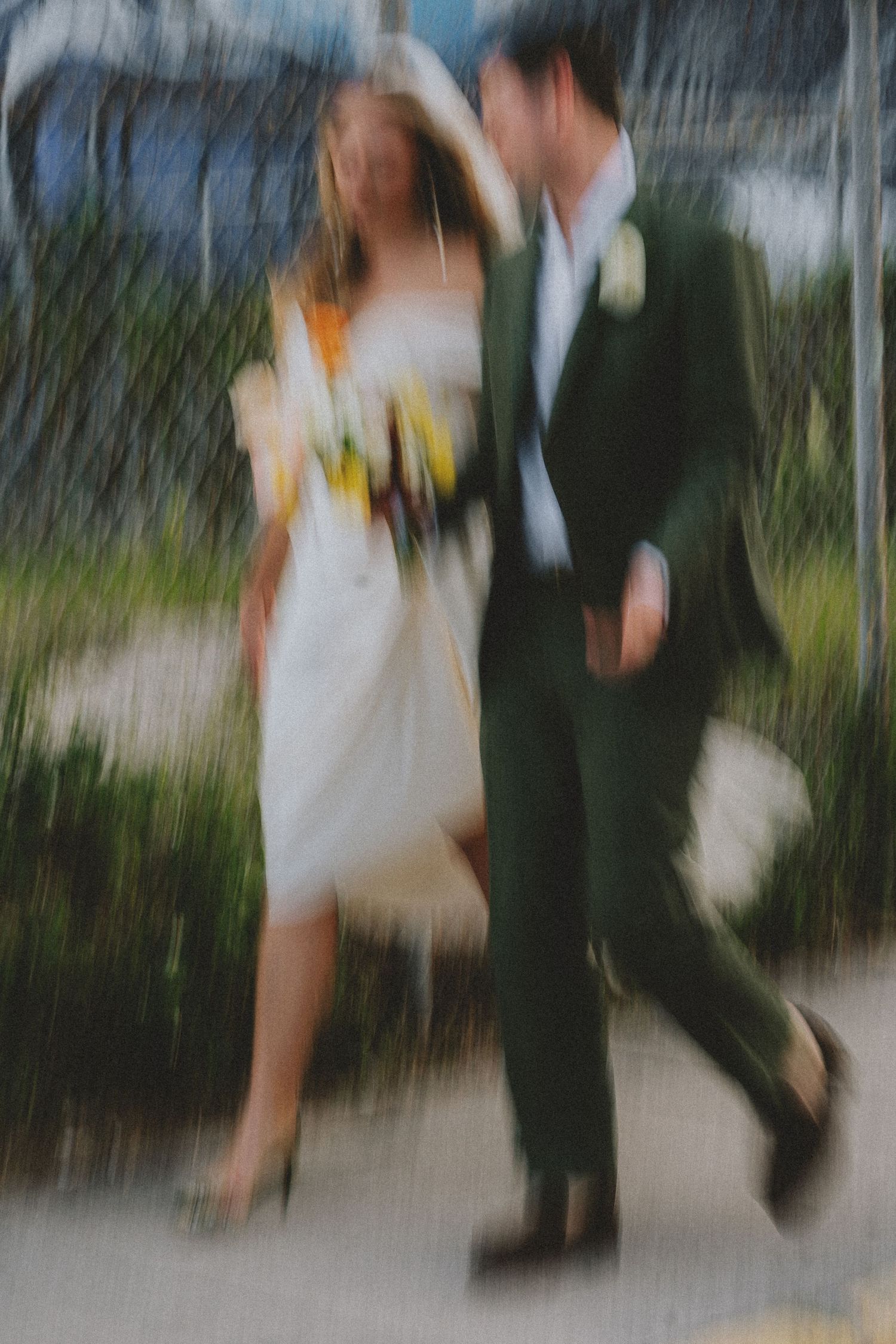Bride and groom walking together in motion blur holding colorful bouquet on wedding day.