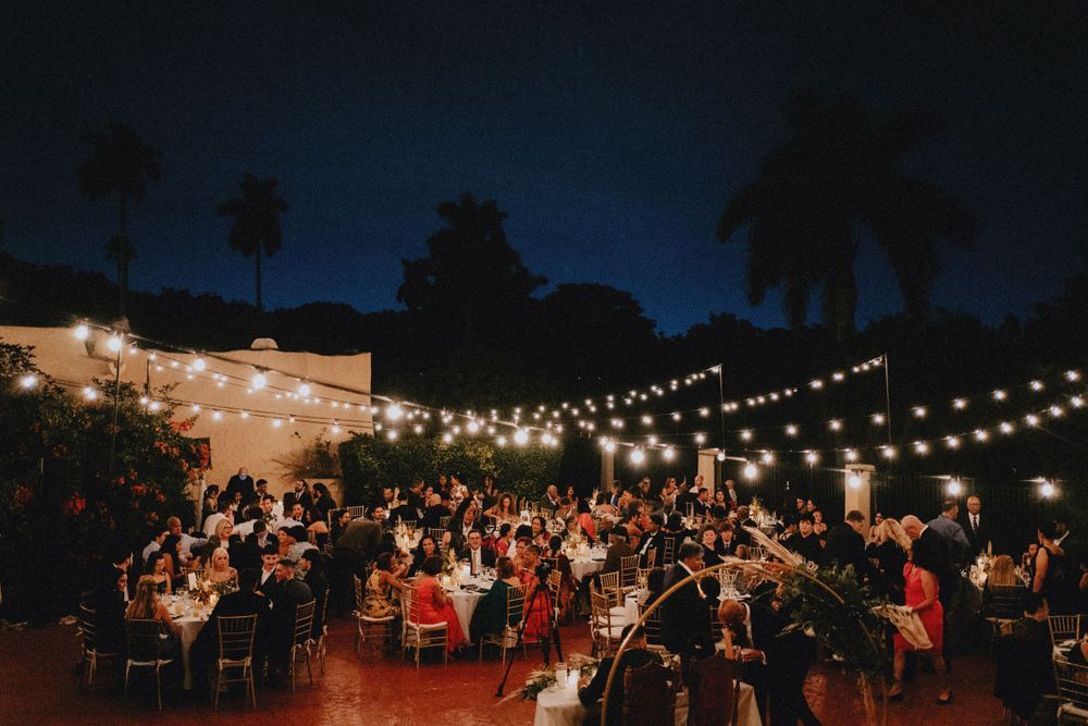 Outdoor evening reception venue with string lights creating a warm ambiance over dining tables.
