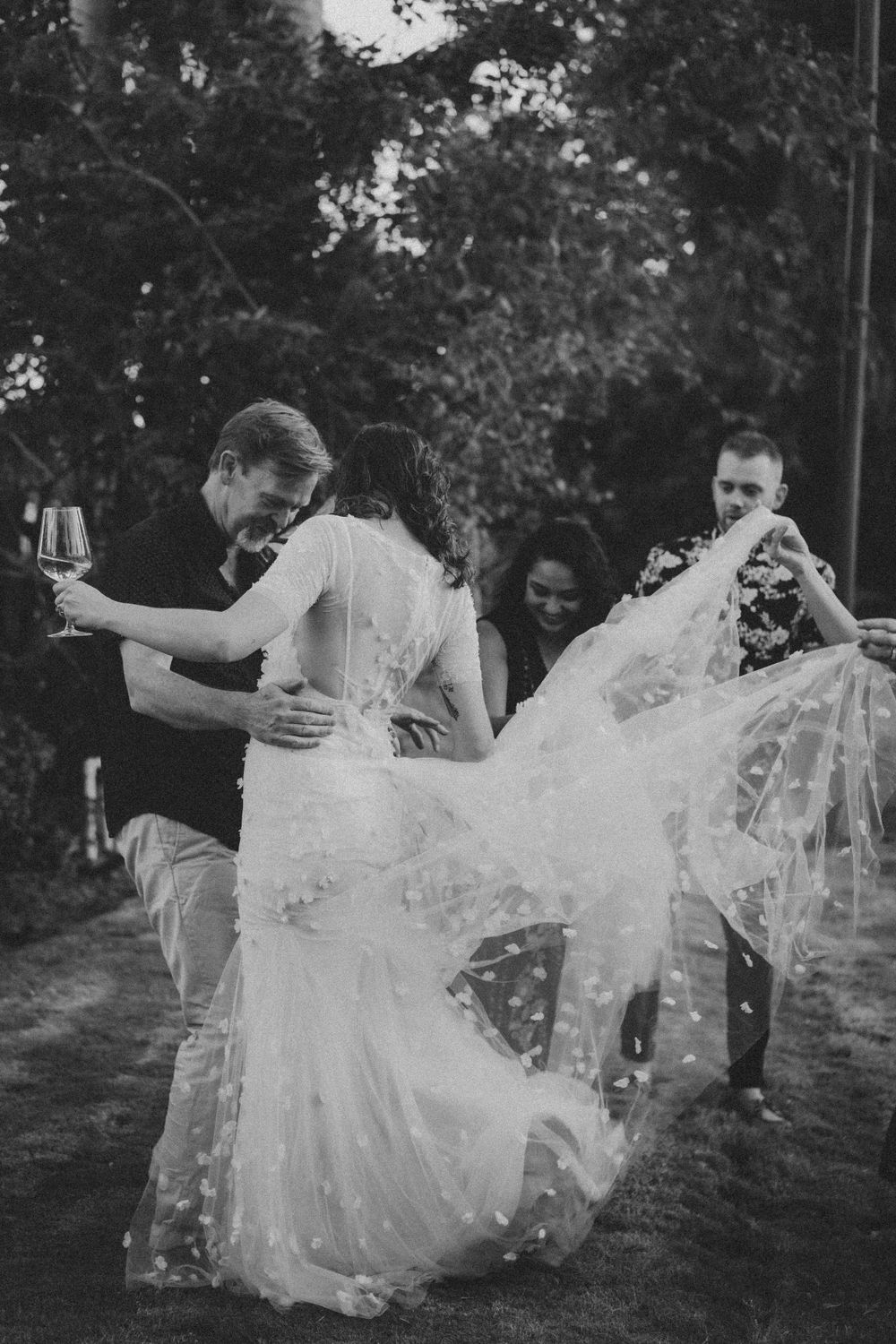 Black and white photo of a flowing white wedding dress twirling in an outdoor setting.
