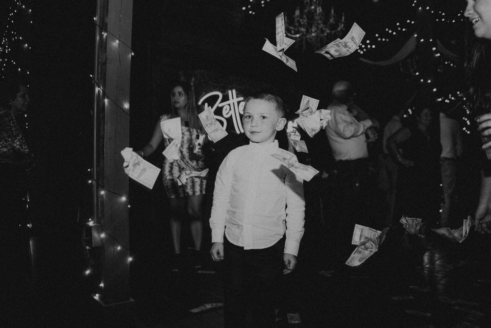 Wedding guests dancing and celebrating on a dark dance floor with twinkling lights overhead.