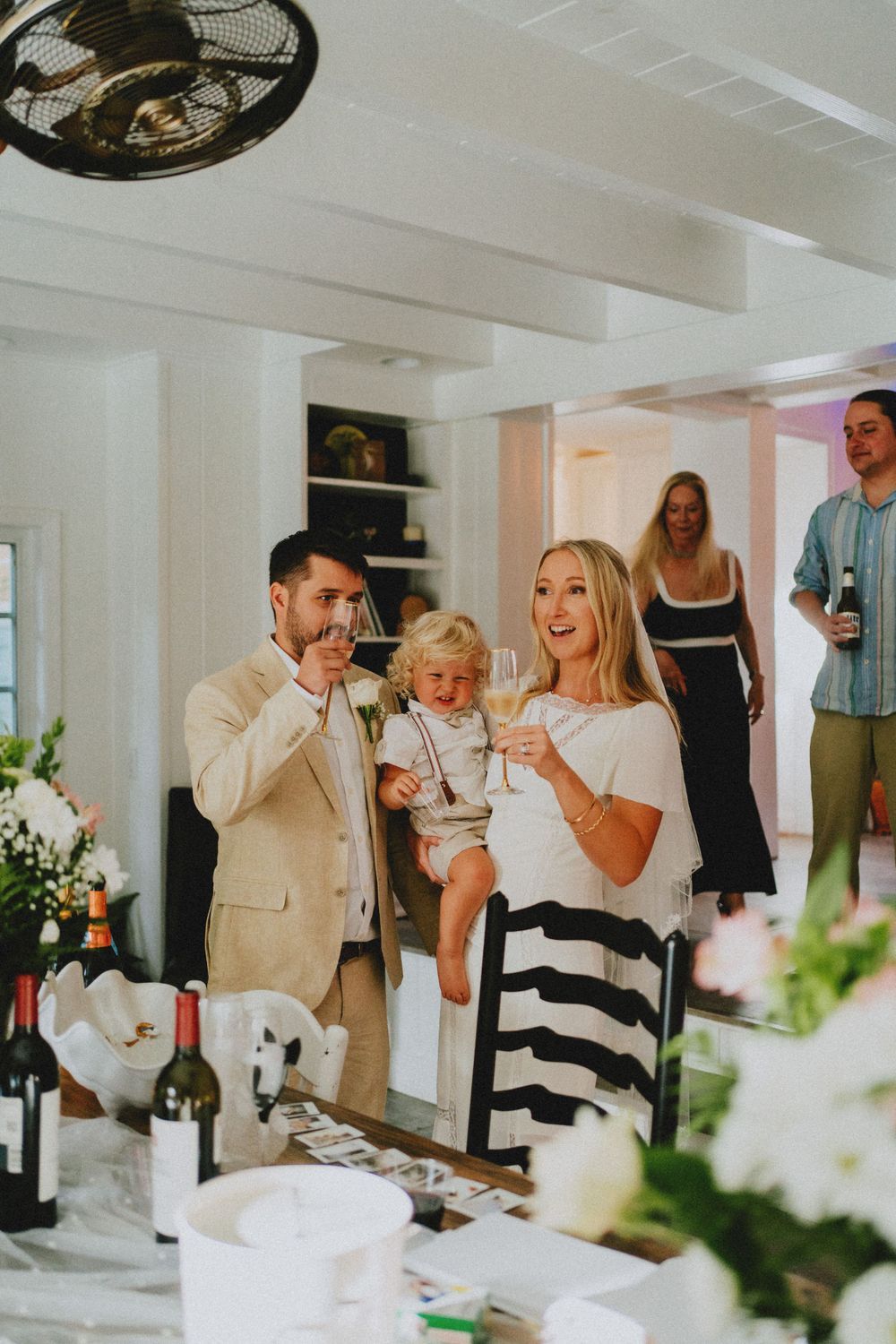 Wedding reception scene in bright white room with floral decorations.