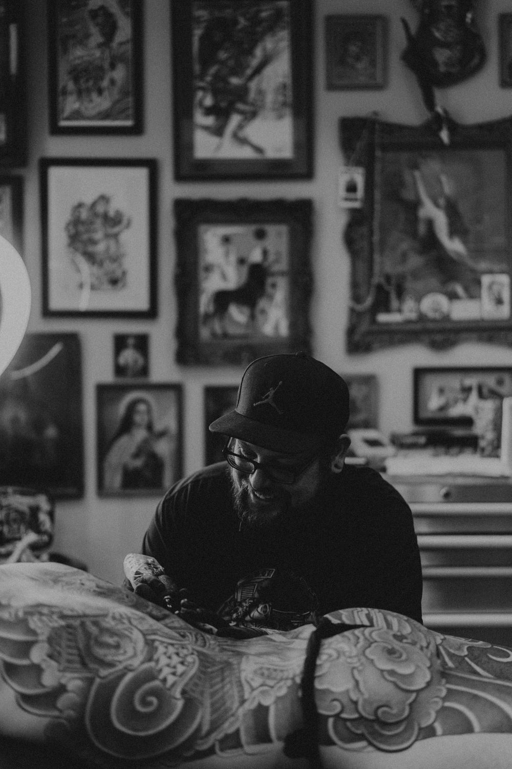 Black and white photo of artwork on walls with decorative framed pieces creating a gallery wall aesthetic.