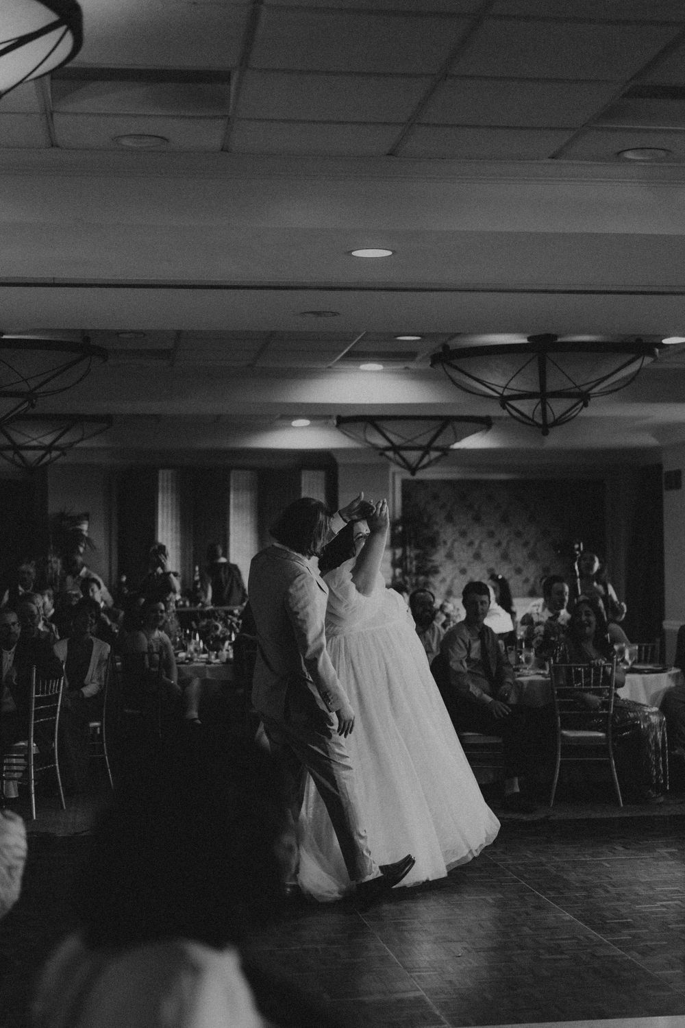 Wedding reception dance floor scene in dramatic black and white lighting.