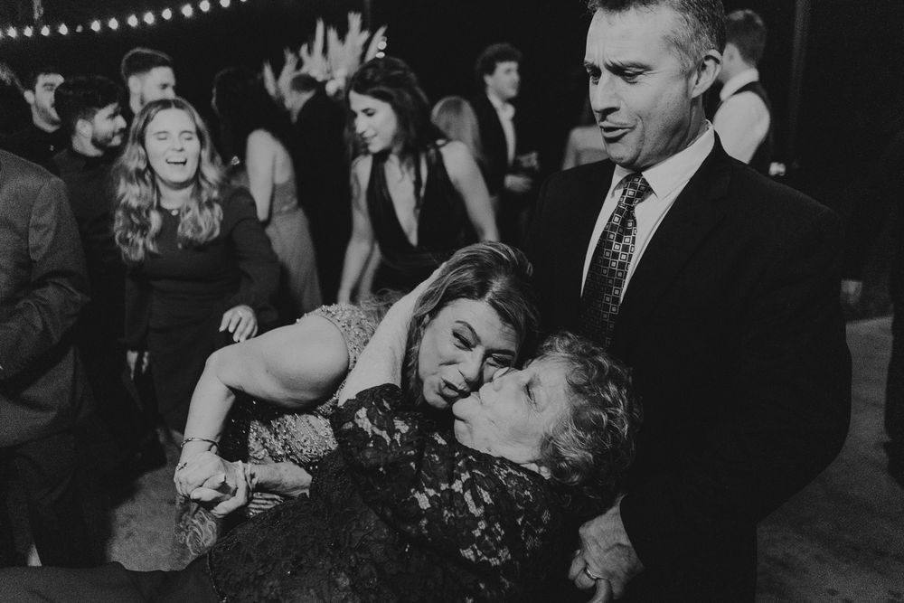 Black and white candid shot of wedding reception guests dancing and celebrating.