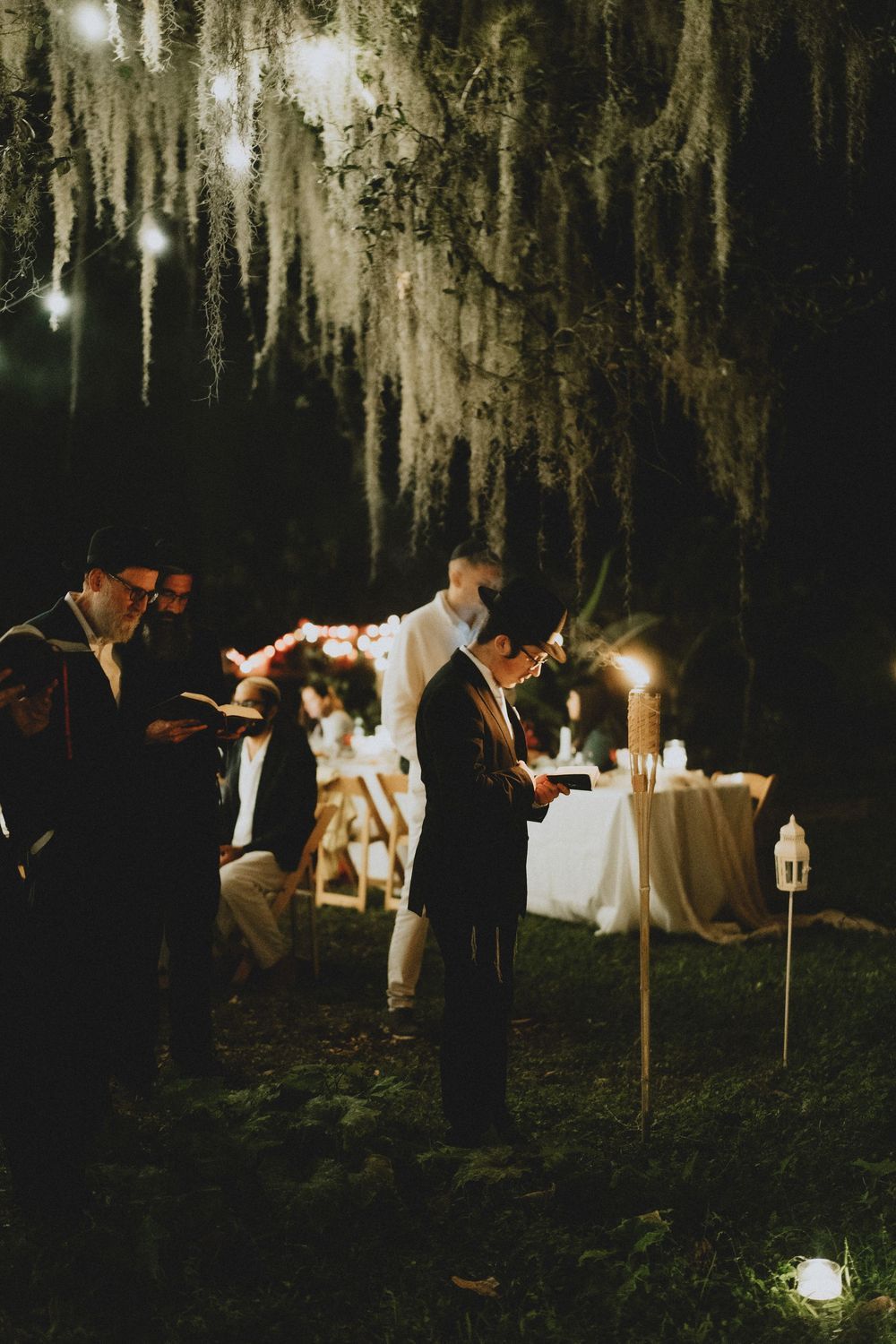 Musicians performing at night under Spanish moss with candle lighting.