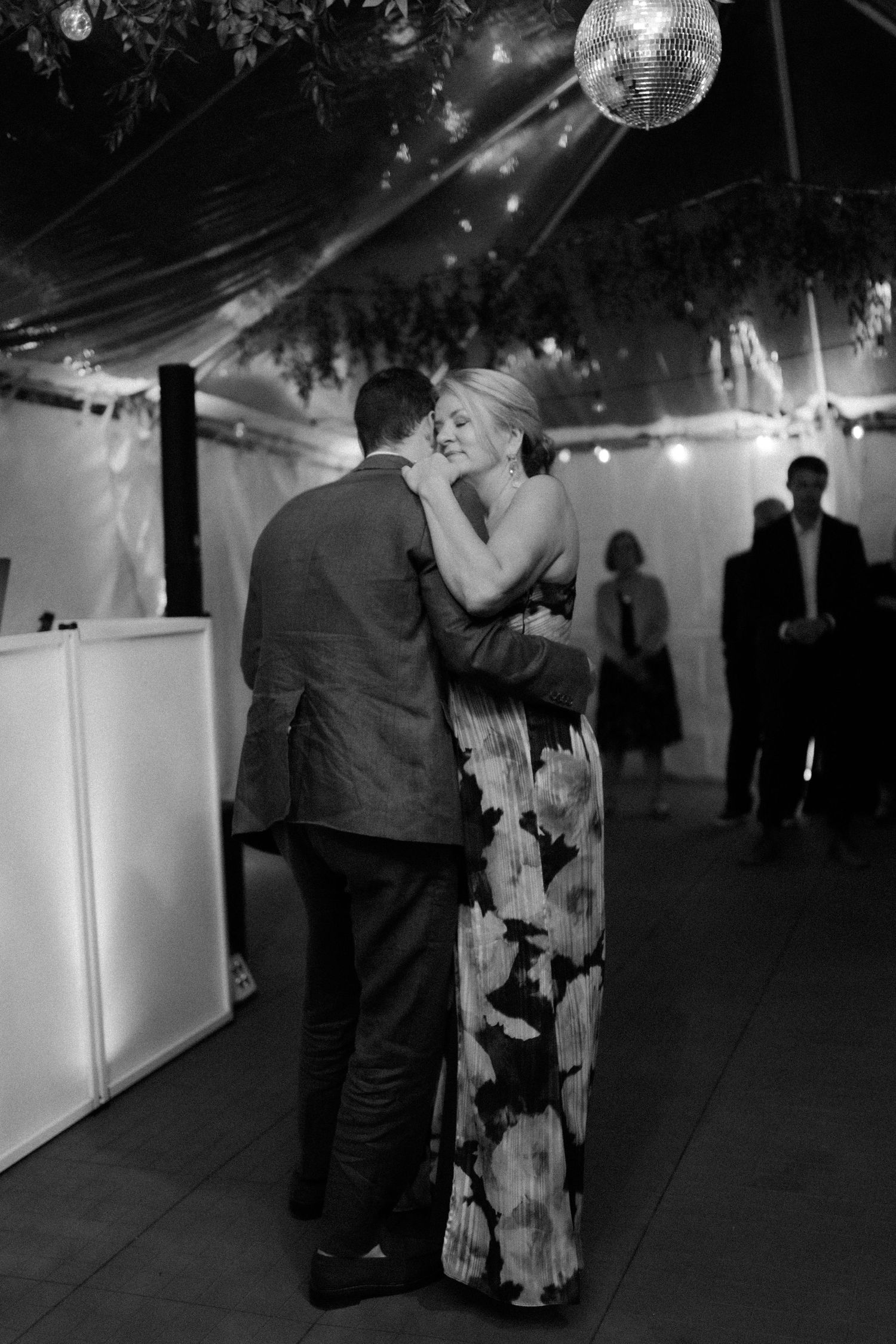 Couple shares romantic first dance under a disco ball at elegant black and white wedding reception.