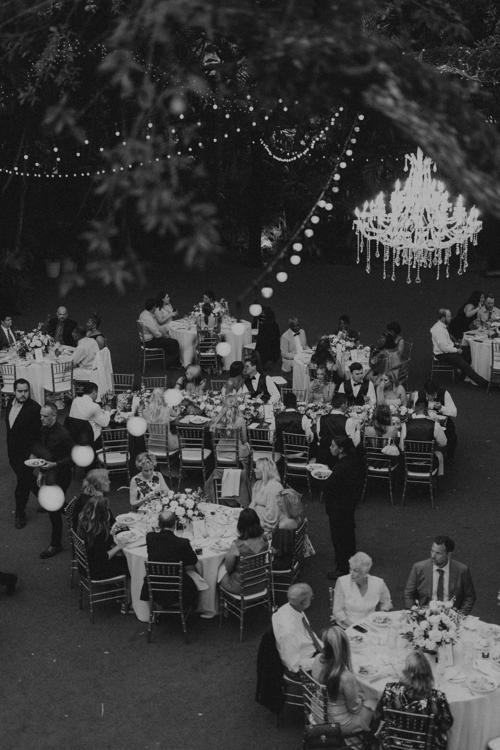 Elegant outdoor wedding reception with string lights and tables set up under dark evening sky.