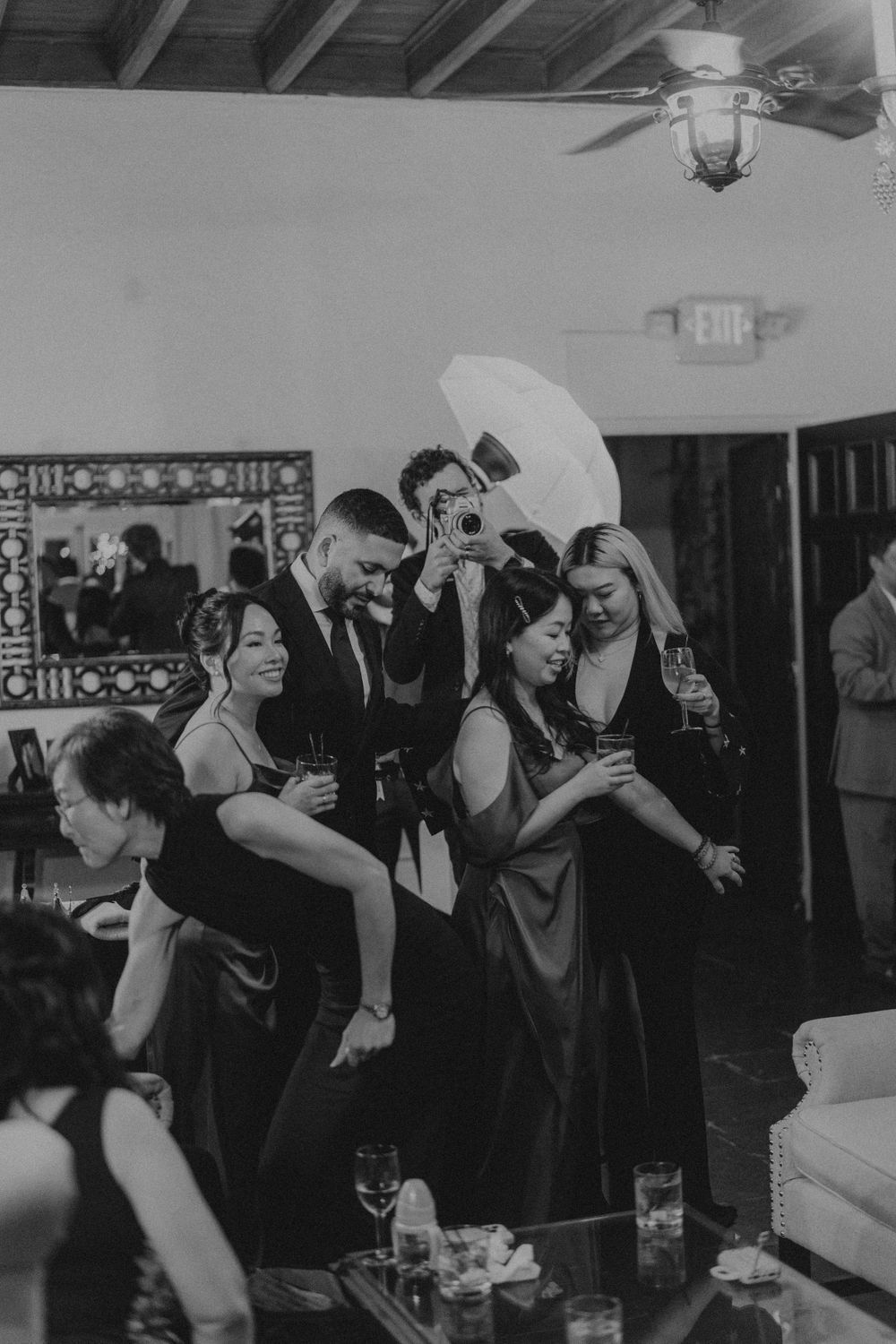 Black and white photo of wedding reception guests dancing and celebrating.